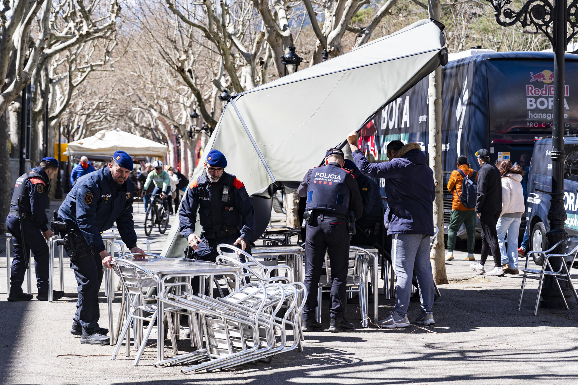 Los Mossos dEsquadrarecogen mobiliario urbano antes de la salida de la sexta etapa de La Volta que ha sido neutralizada debido a las fuertes rachas de viento y están haciendo una ruta alternativa en grupo. EFE/ Siu Wu