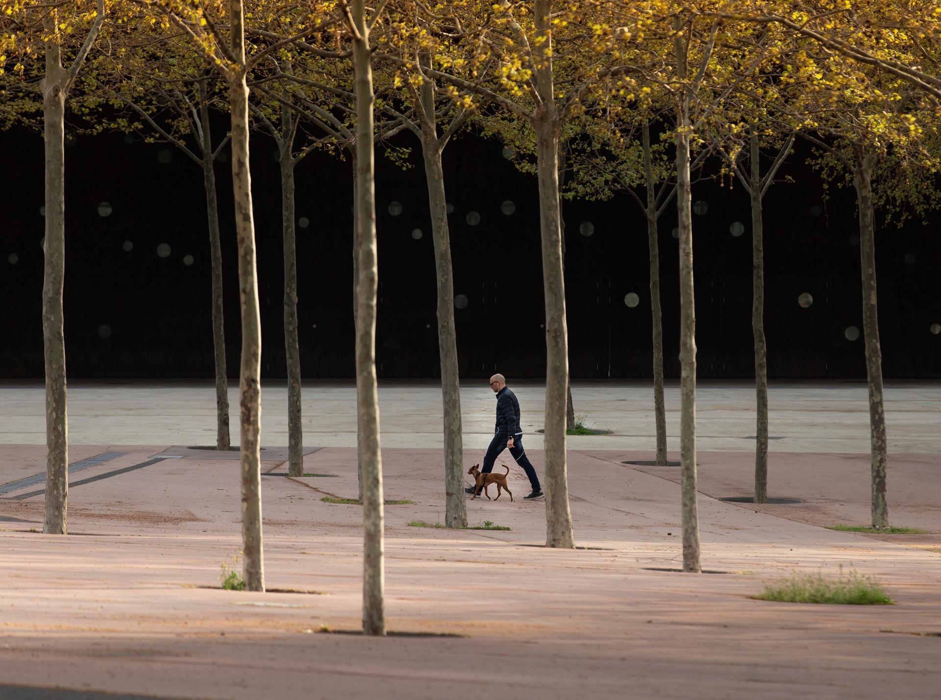En la imagen de archivo, un hombre pasea con su perro por una de las calles de Barcelona. EFE/Enric Fontcuberta