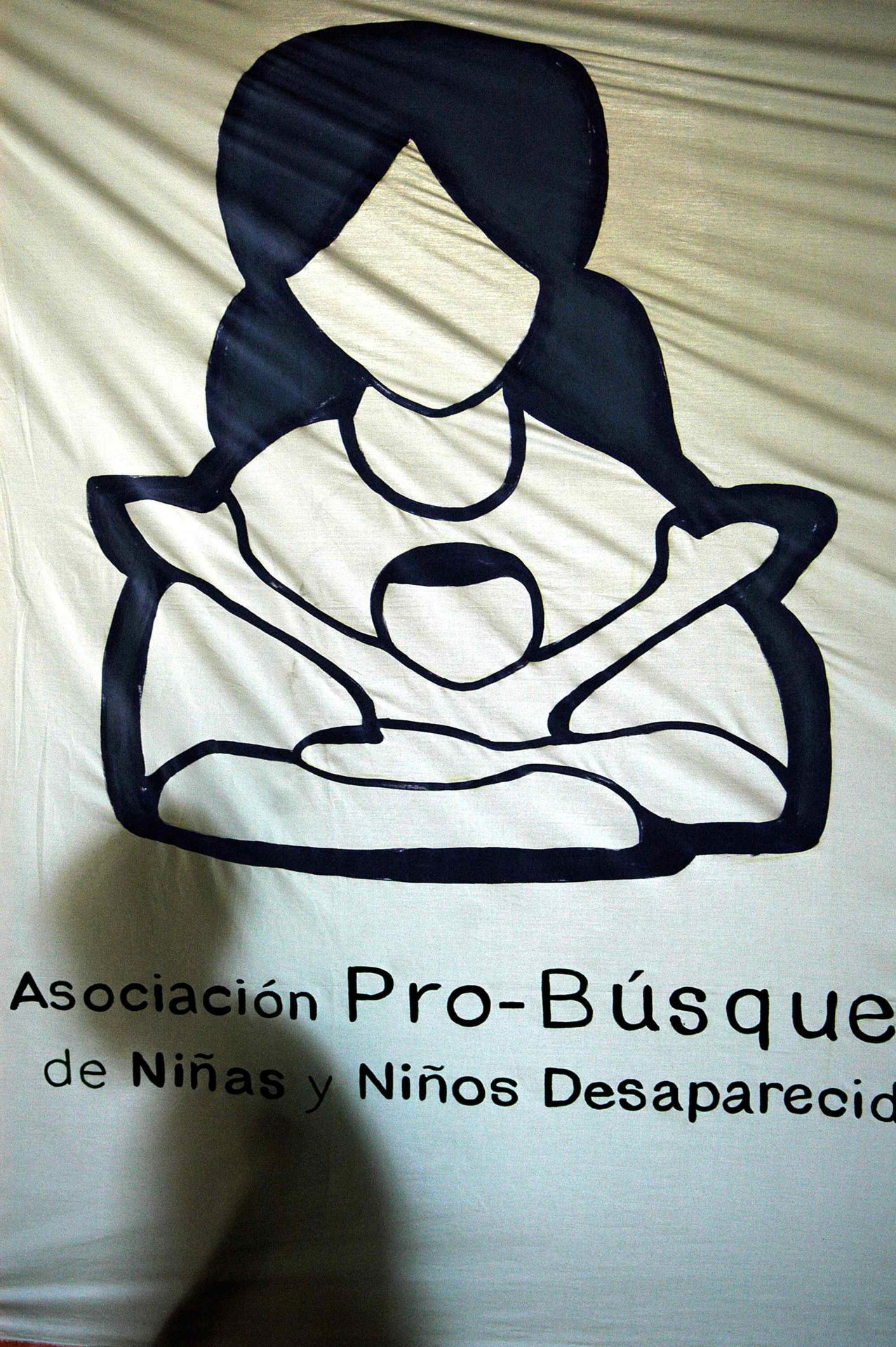 Fotografía de archivo en la que se registró la sombra de un niño al pasar por detrás de un pendón con el logotipo de la Asociación Pro Búsqueda de Niños y Niñas Desaparecidos durante la guerra civil (1980-1992) en El Salvador. EFE/Roberto Escobar