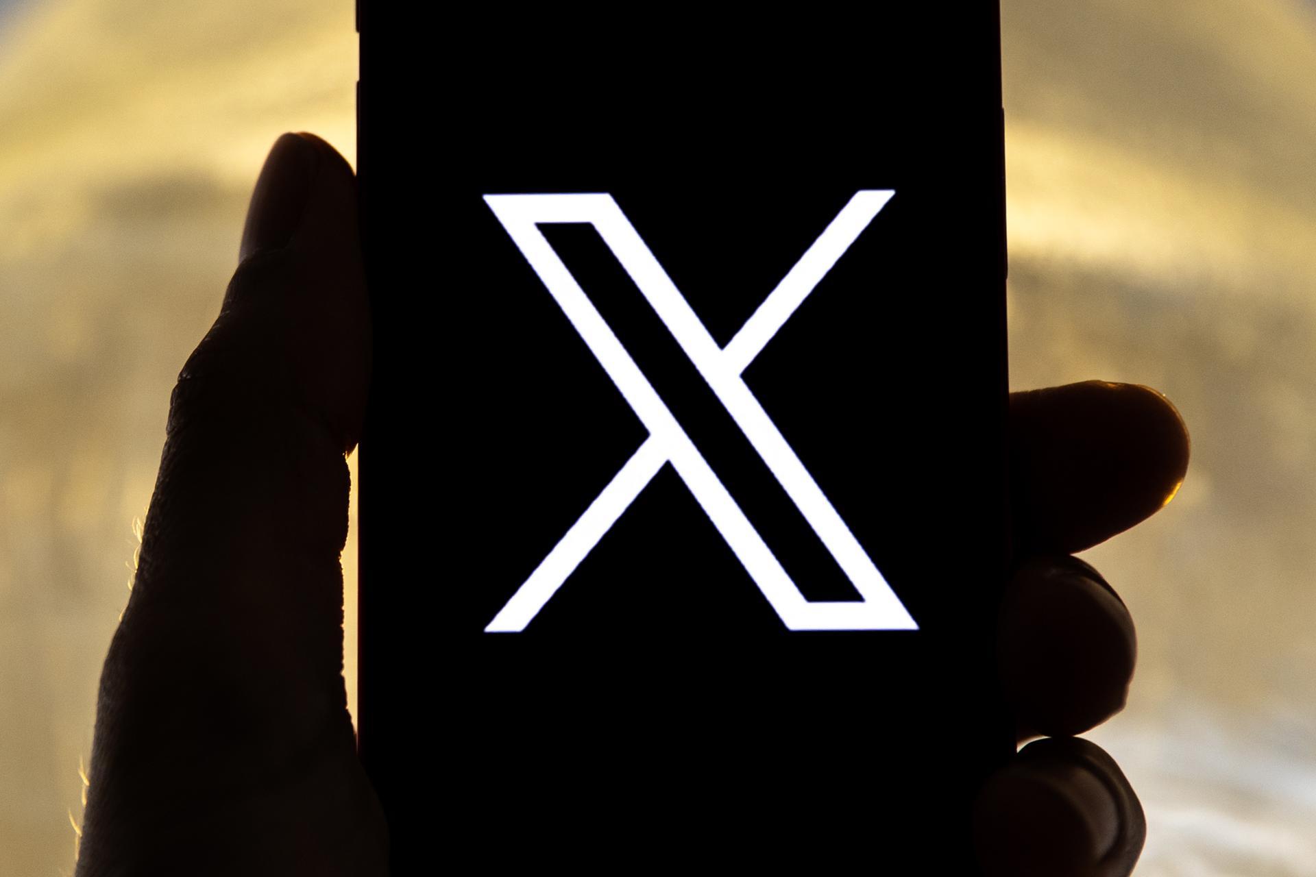 Fotografía de archivo en la que se registró la mano de una persona al sostener un teléfono móvil con el logo de la red social X en su pantalla, en Los Ángeles (CA, EE.UU.). EFE/Etienne Laurent