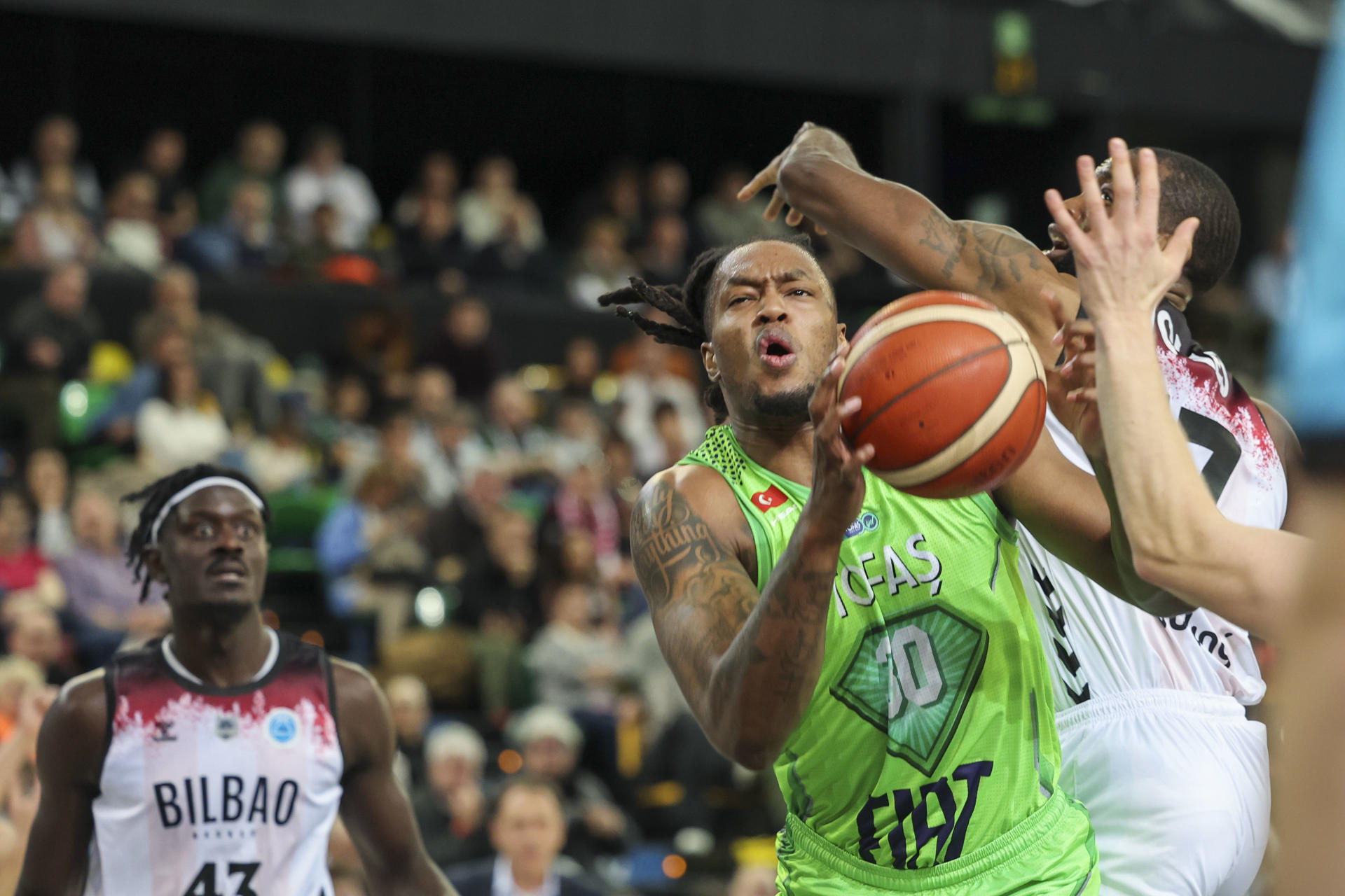 El ala pívot estadounidense del Tofas Kris Bankston (c) entra ante dos rivales del Bilbao Basket, durante el partido de la Copa Europa FIBA de baloncesto en el Bilbao Arena. EFE/ Luis Tejido