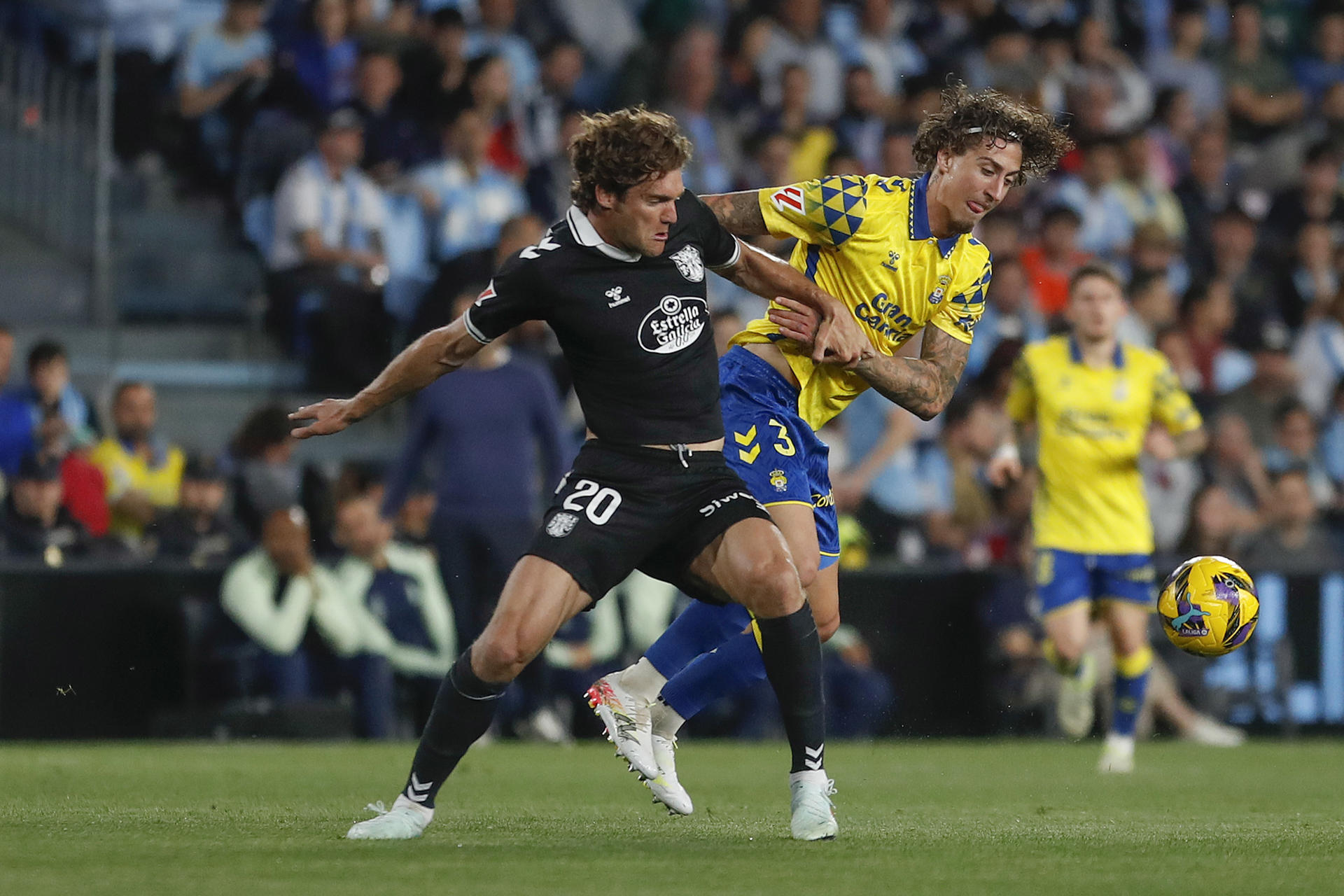 El defensa del Celta Marcos Alonso (i) pelea por un balón ante el defensa de Las Palmas Mika Mármol este lunes, durante el partido de la jornada 29 de LaLiga EA Sports, entre el Celta de Vigo y el UD Las Palmas, celebrado en el estadio de Balaidos en Vigo (Galicia). EFE/ Salvador Sas