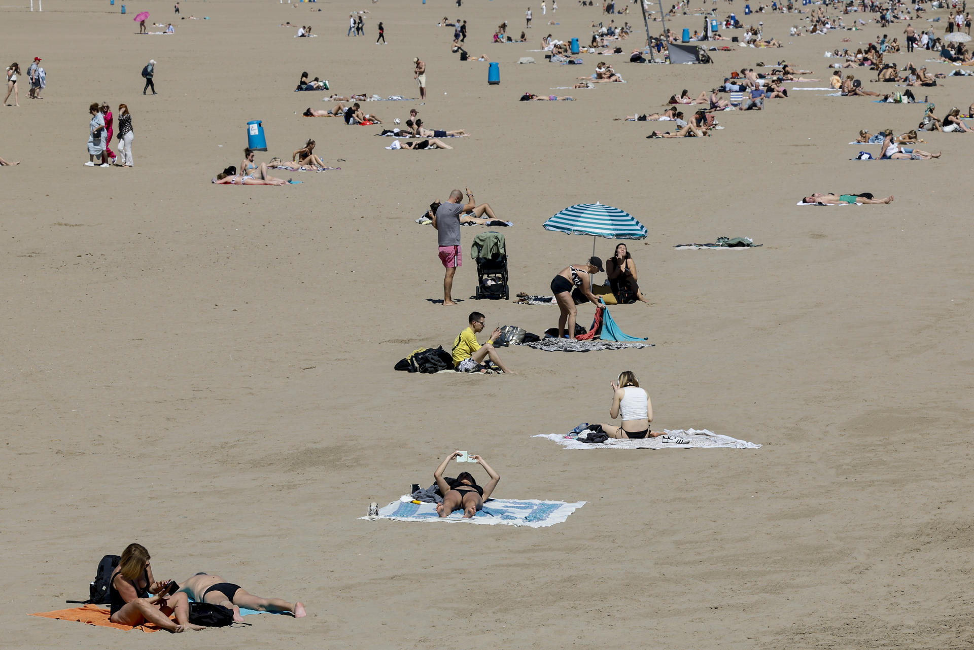 Un gran número de personas disfruta del buen tiempo en la playa de la Malarrosa durante este último día de marzo poco nuboso o despejado con temperaturas al alza. EFE/Ana Escobar
