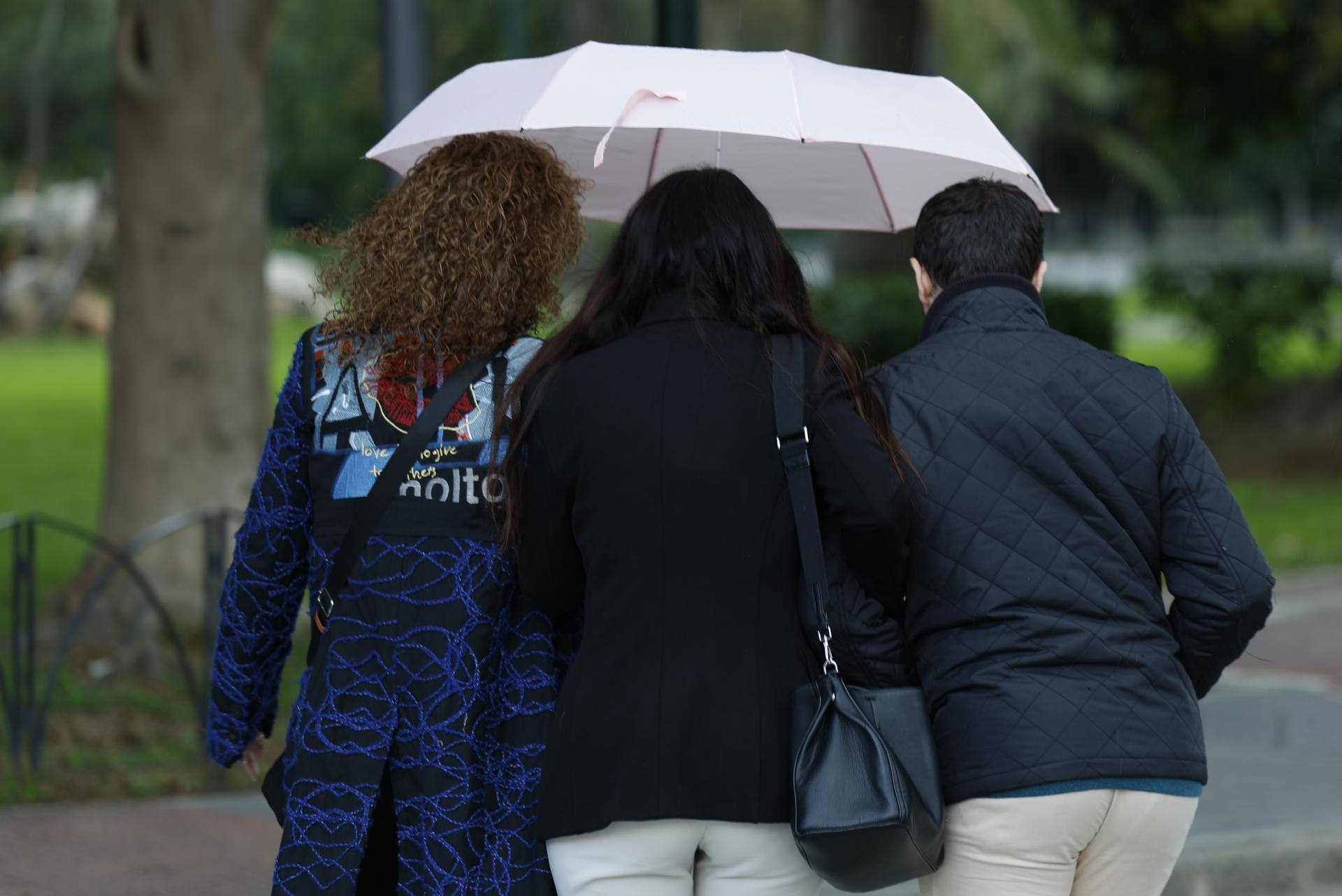 Tres personas se resguardan debajo de un paraguas este miércoles en Málaga en el que la lluvia ha regresado después de una breve tregua. EFE/ Jorge Zapata