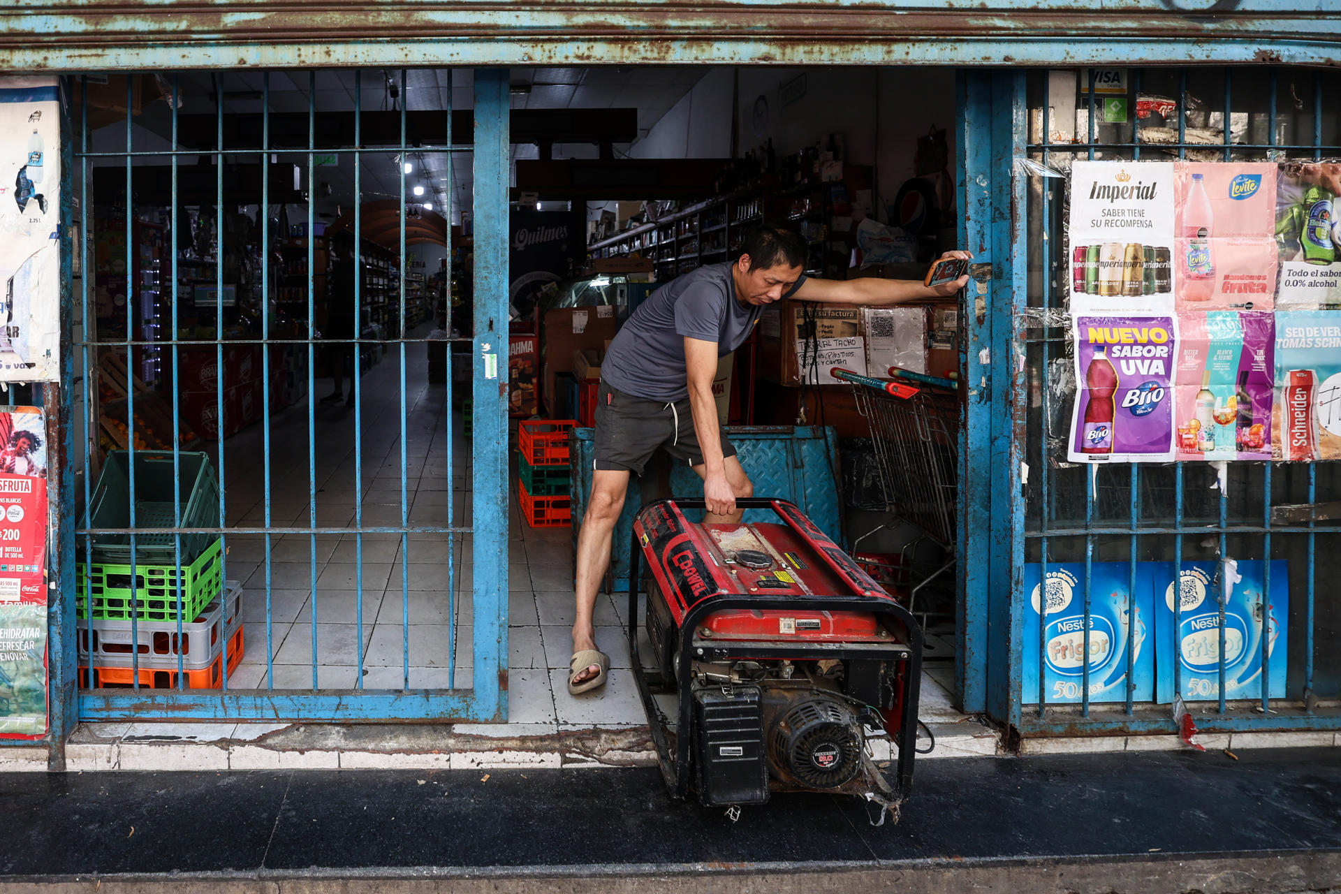 Un hombre fue registrado este miércoles, 5 de marzo, al instalar un generador eléctrico propio en su negocio, durante un apagón en el sur de Buenos Aires (Argentina). EFE/Juan Ignacio Roncoroni
