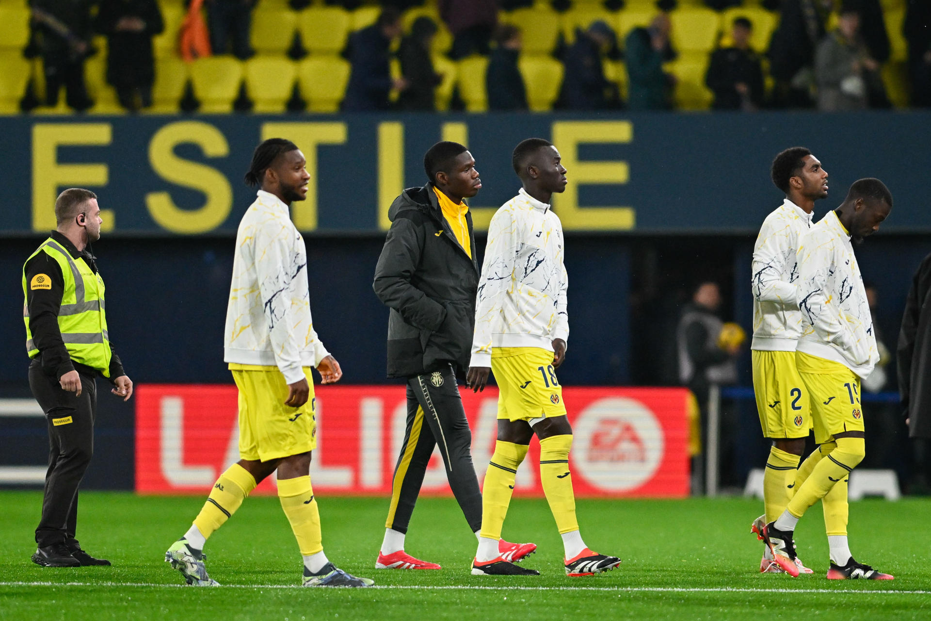 Jugadores del Villarreal abandonan el terreno de juego tras conocerse la suspensión por la lluvia del encuentro correspondiente a la jornada 26 de Laliga EA Sports que iban a disputar hoy lunes Villarreal y RCD Espanyol en el estadio de La Cerámica, en la localidad castellonense. EFE / Andreu Esteban.