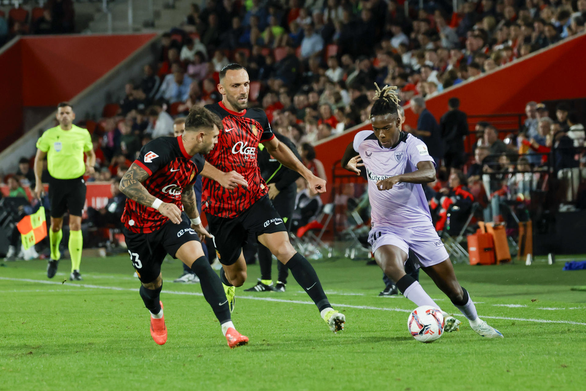 El delantero del Athletic Nico Williams (d), trata de superar a Vedat Muriqi (c) y Pablo Maffeo, ambos del Mallorca, durante el partido de Liga disputado en Son Moix, el 28 d octubre de 2024. EFE/Cati Cladera