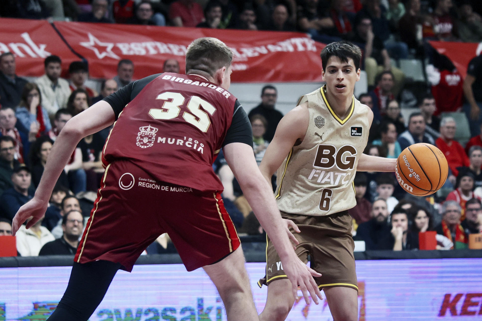 El base de Basquet Girona, Juani Marcos (d), con el balón ante el pivot sueco de UCAM Murcia, Simon Birgander, durante el encuentro correspondiente a la fase regular de la Liga Endesa que disputaron en el Palacio de los Deportes de Murcia. EFE/Juan Carlos Caval.