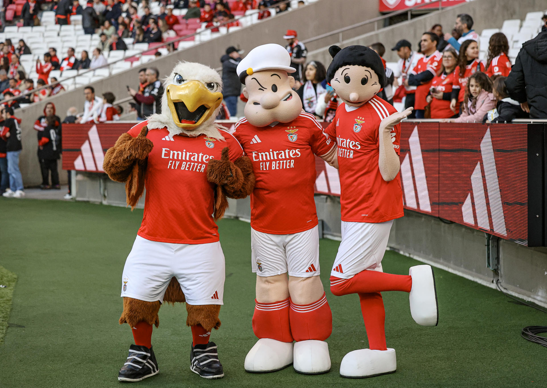 El famoso marino Popeye, junto a Olivia, ha desembarcado en Portugal vestido con los colores del Benfica en una colaboración que celebra sus 95 años como símbolo mundial de salud y resistencia. A la izquierda, la mascota oficial del equipo luso, Águila Vitória. EFE/Cedida por Hearst/Isabel Cutileiro/SOLO USO EDITORIAL