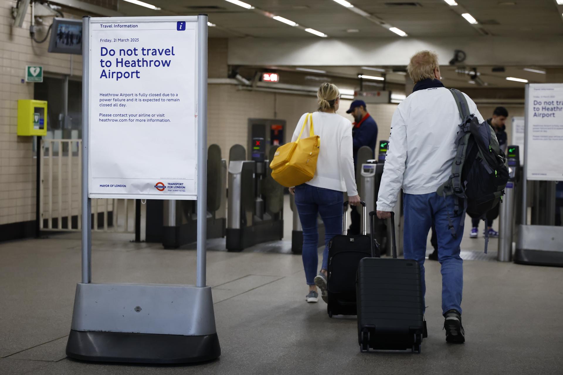 Viajeros en la estación de metro de Hatton Cross pasan junto a un cartel que aconseja no viajar al aeropuerto de Heathrow en Londres, el 21 de marzo de 2025.EFE/EPA/TOLGA AKMEN