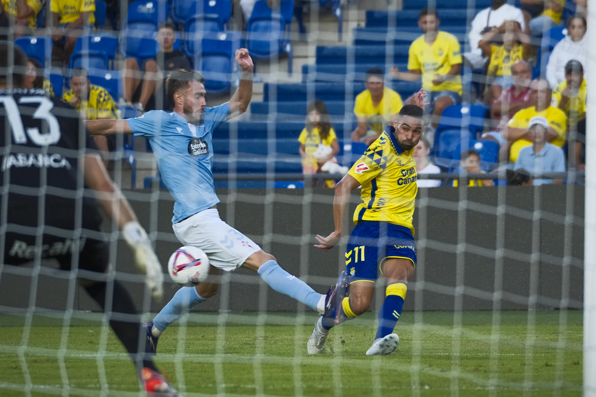 El centrocampista de la UD Las Palmas Benito Ramírez (d) centra el balón ante el defensa del Celta Óscar Mingueza (c) en el estadio de Gran Canaria en foto de archivo de Angel Medina G.EFE