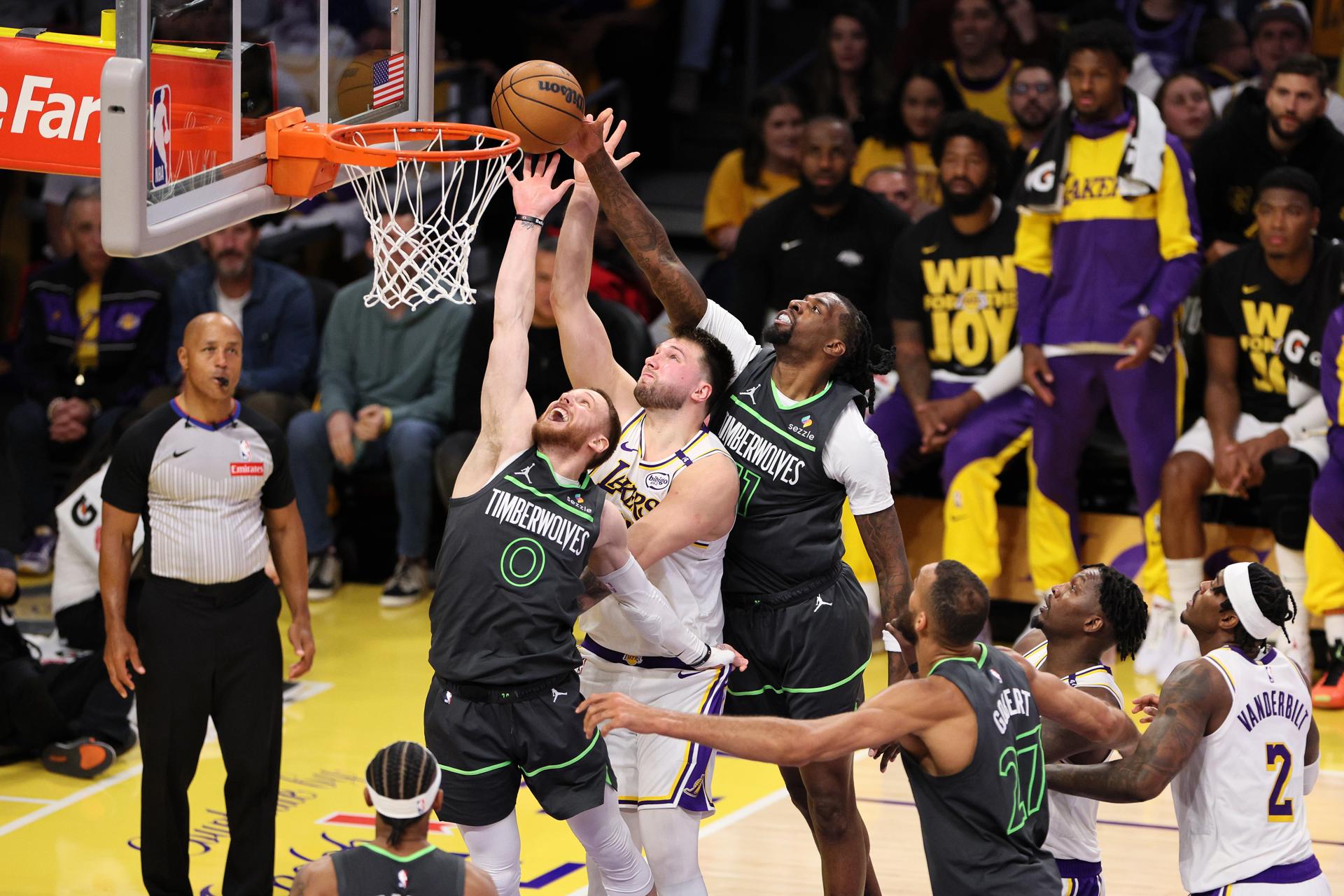 Luca Doncic de Los Angeles Lakers (c) lanza con la marca de Donte DiVincenzo (i) y Naz Reid (d) de los Minnesota Timberwolves. EFE/ALLISON DINNER