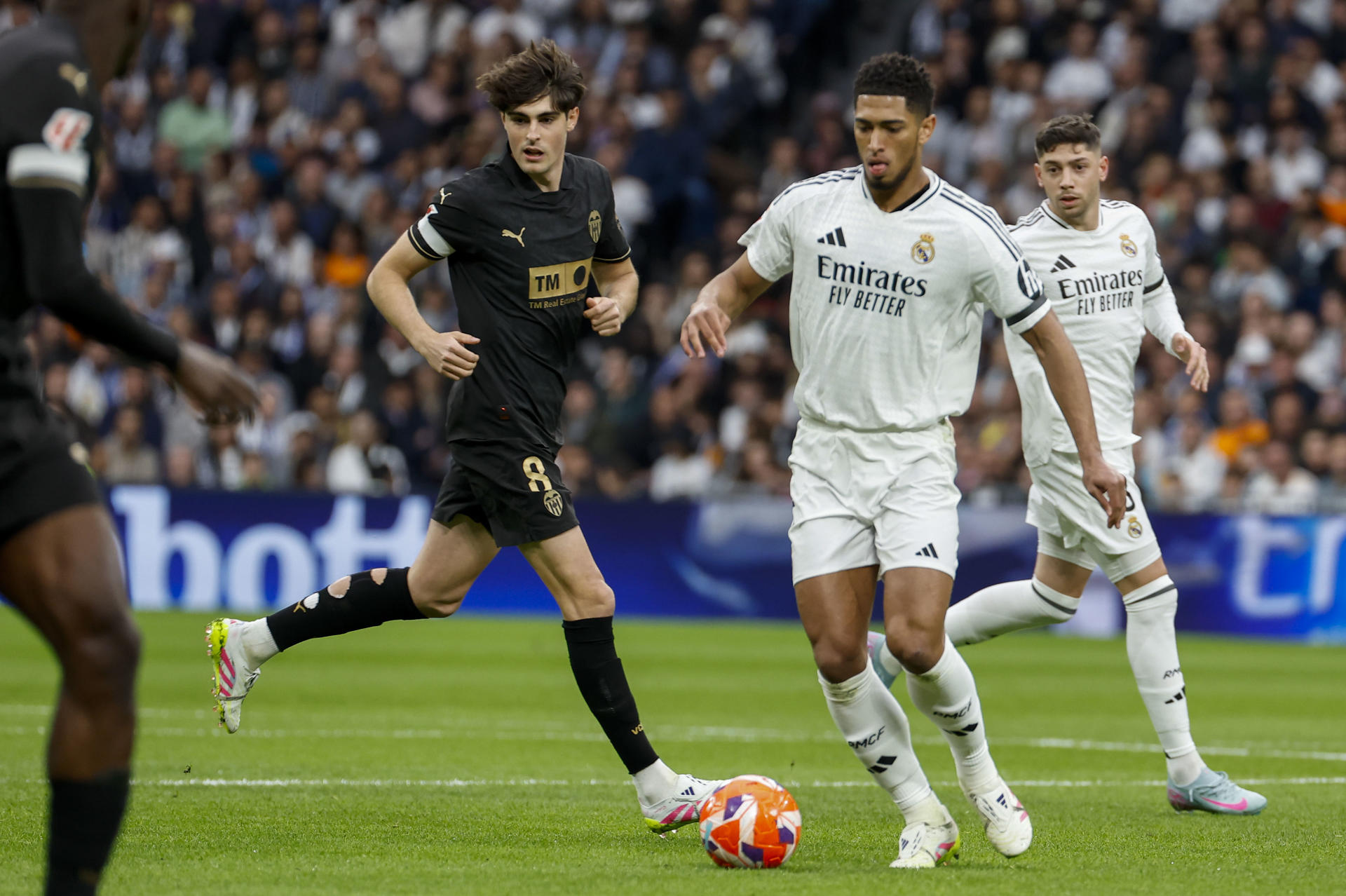 El centrocampista inglés del Real Madrid Jude Bellingham (d) pelea un balón con el centrocampista del Valencia Javi Guerra durante el partido de LaLiga entre el Real Madrid y el Valencia disputado en el estadio Santiago Bernabéu en Madrid. EFE/Chema Moya
