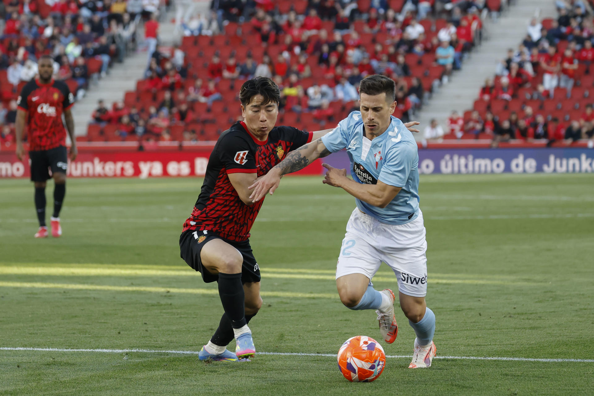 El centrocampista japonés del Mallorca Takuma Asano (i) pelea un balón con el delantero del Celta Alfonso González durante el partido de LaLiga entre el Real Mallorca y el Celta, este sábado en el estadio de Son Moix, en Palma. EFE/CATI CLADERA