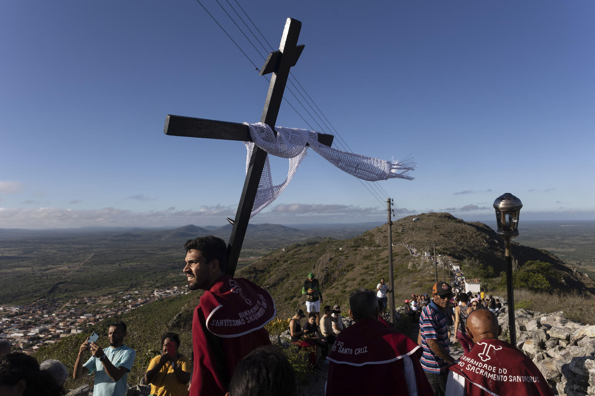 Un hombre sostiene una cruz durante la tradicional procesión al santuario del Monte Santo este viernes, en Monte Santo, Bahía (Brasil). EFE/ Rafael Martins
