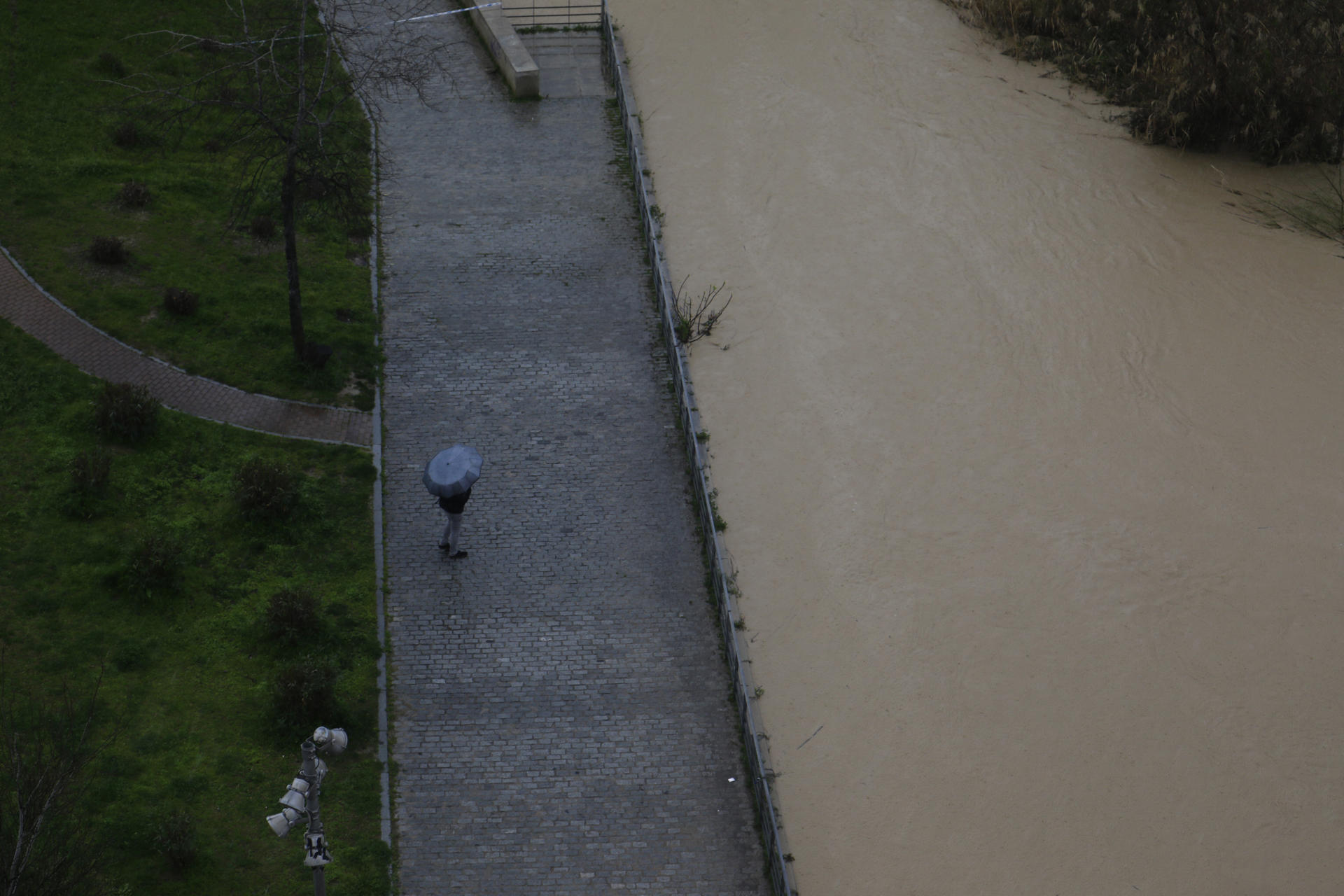Un hombre con paraguas observa la pasarela peatonal, bajo el Puente Romano de Córdoba el pasado mes de marzo. EFE/Salas