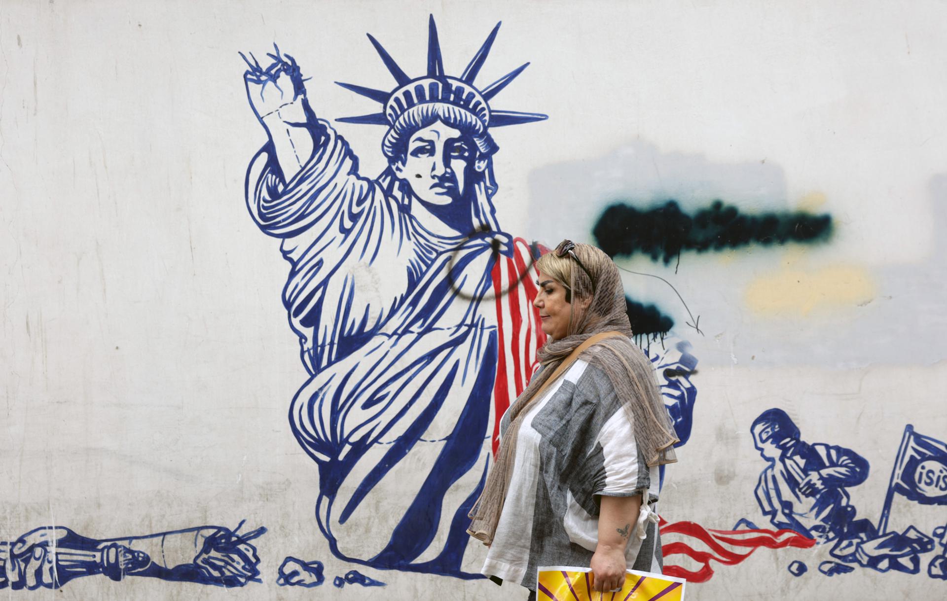 Teherán - Una mujer pasa cerca de un mural antiestadounidense en Teherán este sábado, el mismo día que representantes de Irán y EE.UU se reúnen indirectamente en Omán. EFE/EPA/ABEDIN TAHERKENAREH