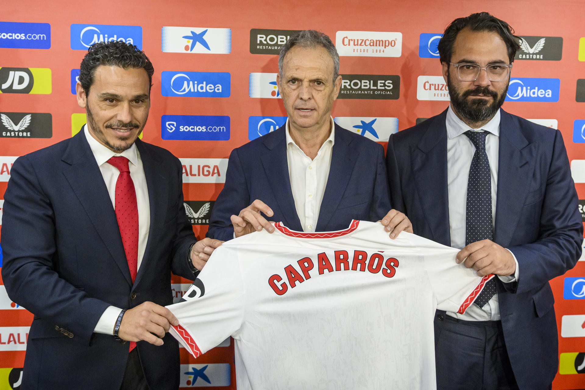 El nuevo entrenador del Sevilla FC, Joaquín Caparrós (c), junto al presidente del club, José María del Nido Carrasco (i), y el director deportivo, Victor Orta (d), durante su presentación en el Sánchez Pizjuán, donde ha dicho que se encuentra "feliz y con la misma energía e ilusión" ante esta cuarta etapa en el banquillo sevillista que cuando llegó "por primera vez en el año 2000'. EFE/Raúl Caro