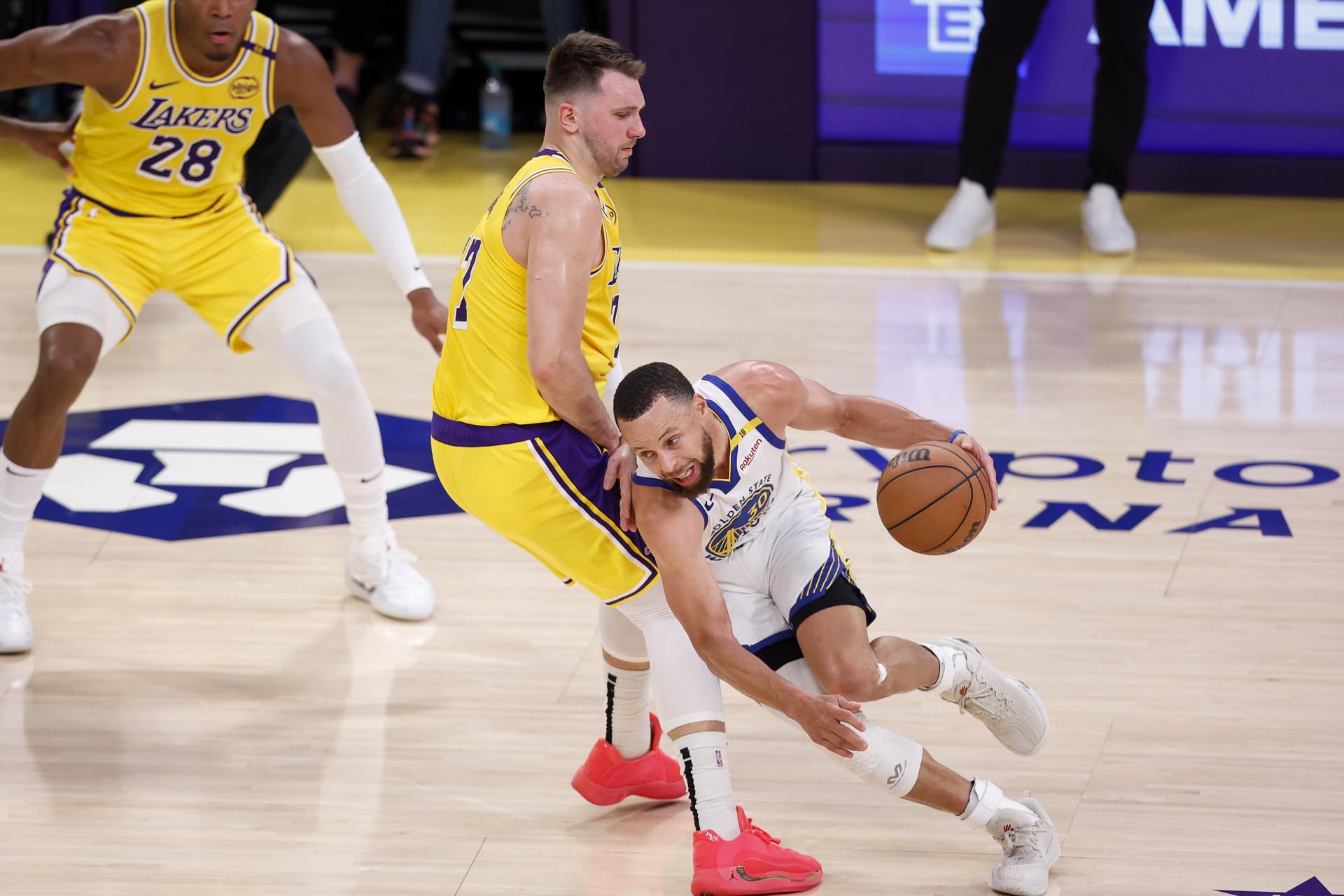 El base de los Golden State Warriors, Stephen Curry (D), supera al escolta de los Los Angeles Lakers, Luka Doncic (C). EFE/EPA/CAROLINE BREHMAN