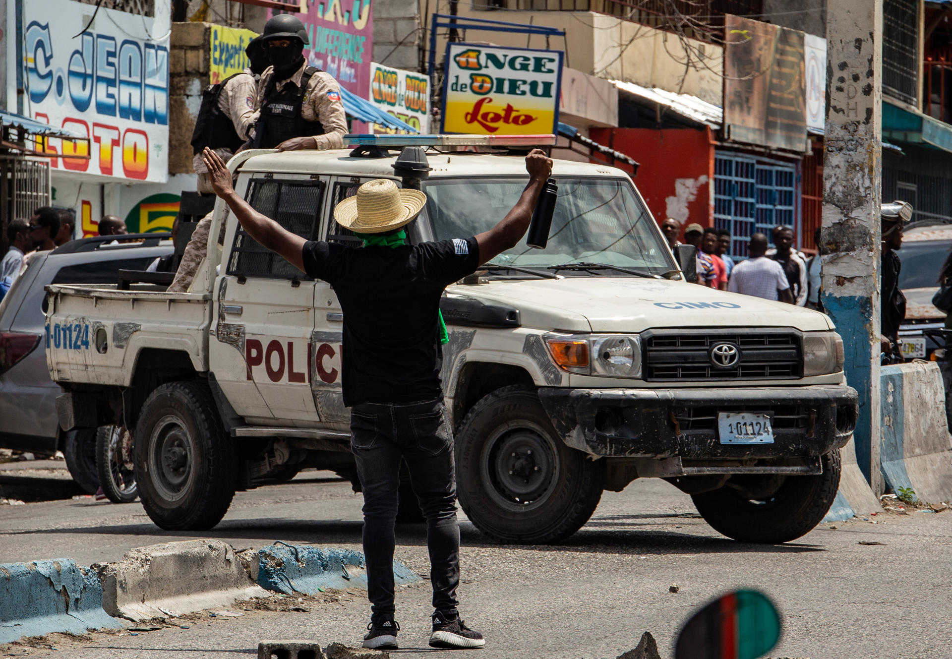 Fotografía del 26 de marzo de 2025 en la cual se ve a un hombre que levanta los brazos frente a unos agentes policiales durante una protesta contra la inseguridad y la violencia en Puerto Príncipe (Haití). EFE/ Mentor David Lorens