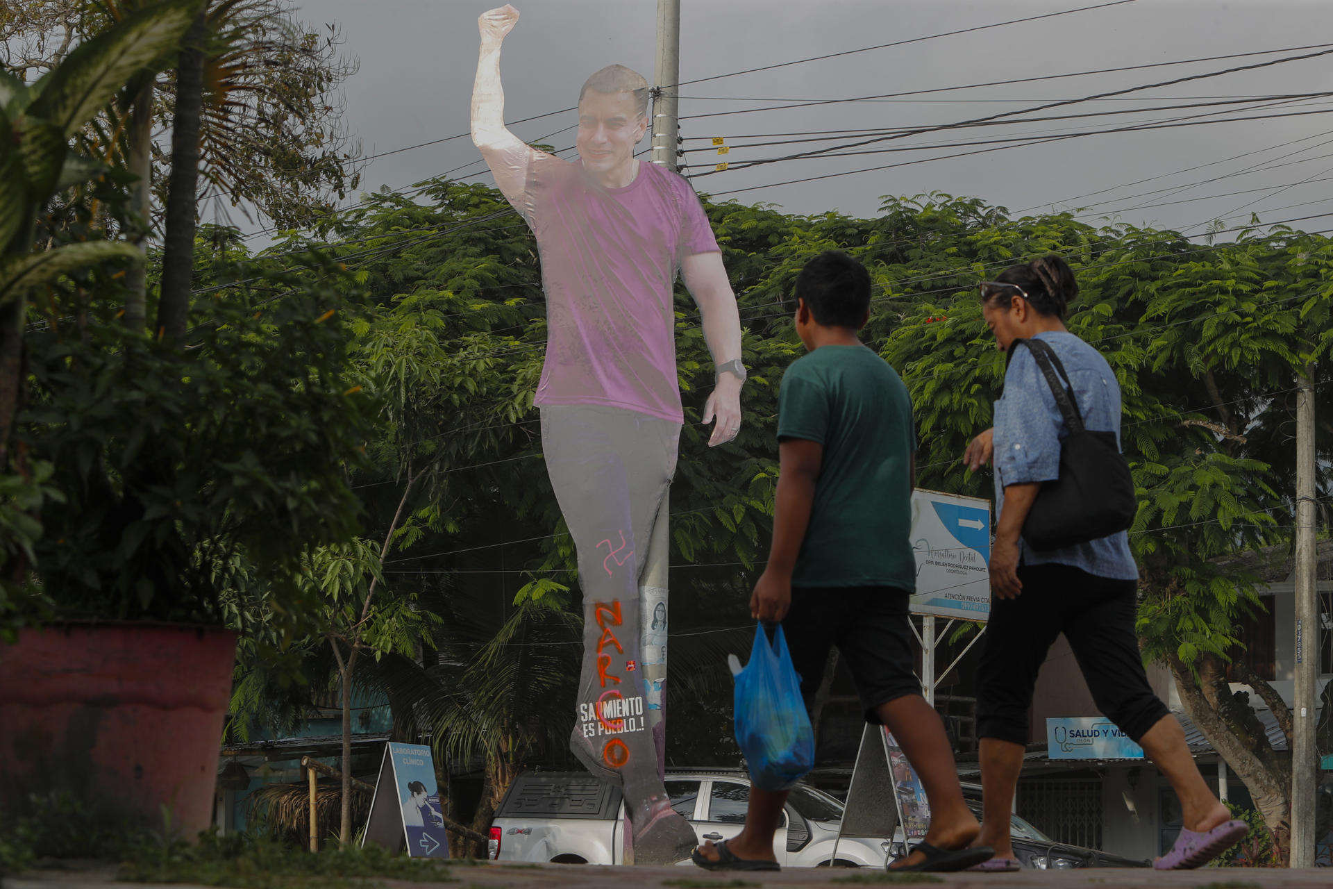 Una pareja pasa frente a una imagen del presidente de Ecuador y candidato a la reelección, Daniel Noboa, este 12 de abril de 2025, en Olón (Ecuador). EFE/ Carlos Durán Araújo