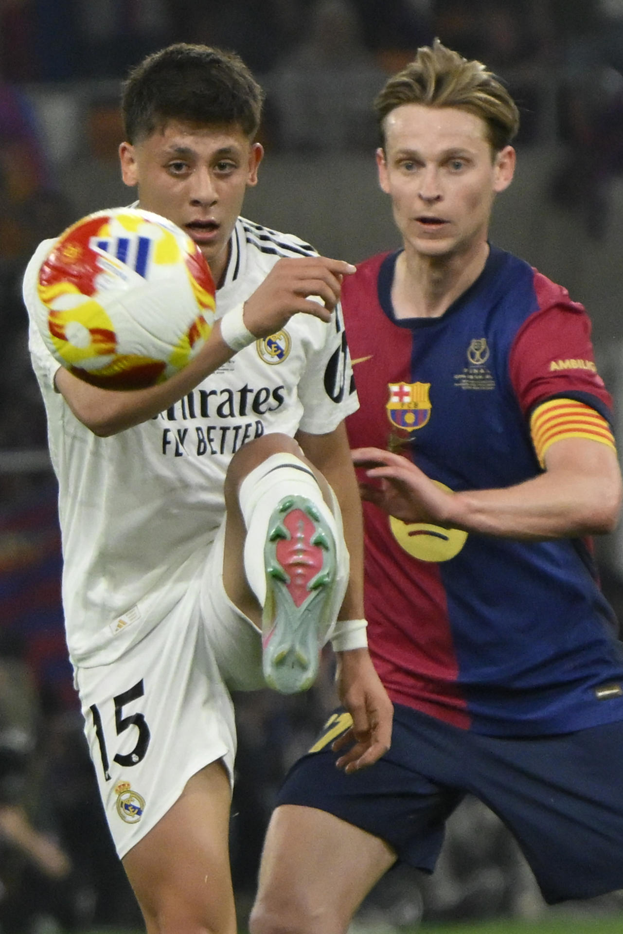El delantero turco del Real Madrid, Arda Guler (i), golpea el balón ante el centrocampista neerlandés del FC Barcelona, Frenkie de Jong, durante el encuentro correspondiente a la final de la Copa del Rey que disputaron Real Madrid y FC Barcelona en el estadio de La Cartuja, en Sevilla. EFE / Raul Caro.