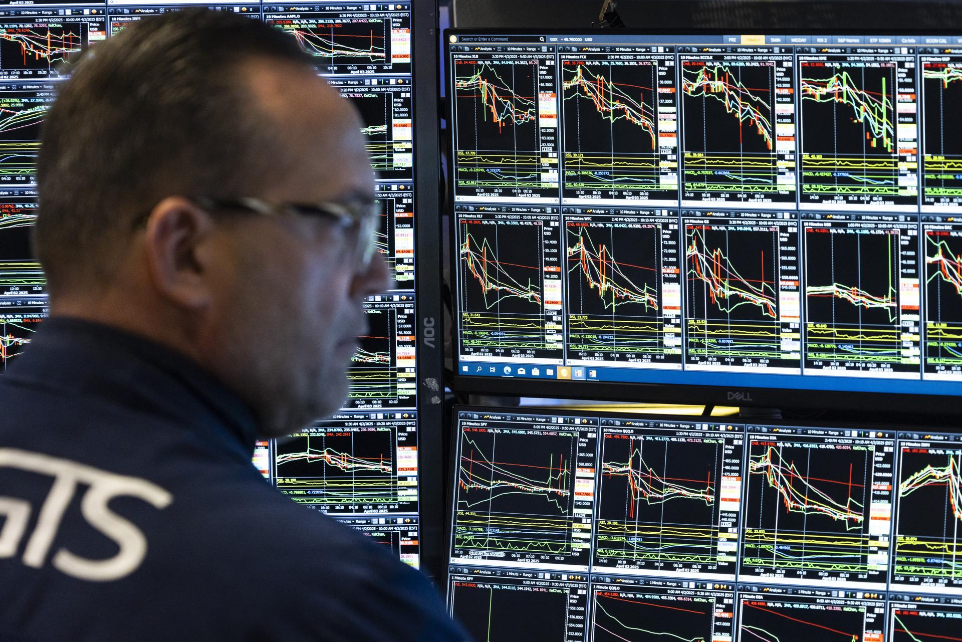 Un corredor de bolsa observa este jueves, 3 de abril, varias pantallas que muestran la variación de los indicadores bursátiles en la Bolsa de Valores de Nueva York, en Wall Street (NY, EE.UU.). EFE/Justin Lane