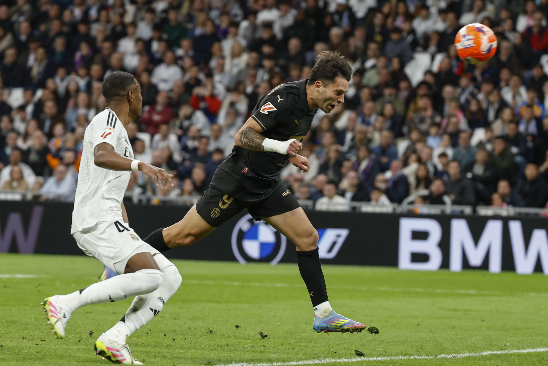 El jugador del Valencia Hugo Duro marca de cabeza durante el partido de LaLiga disputado este sábado en el estadio Santiago Bernabéu. EFE/Chema Moya