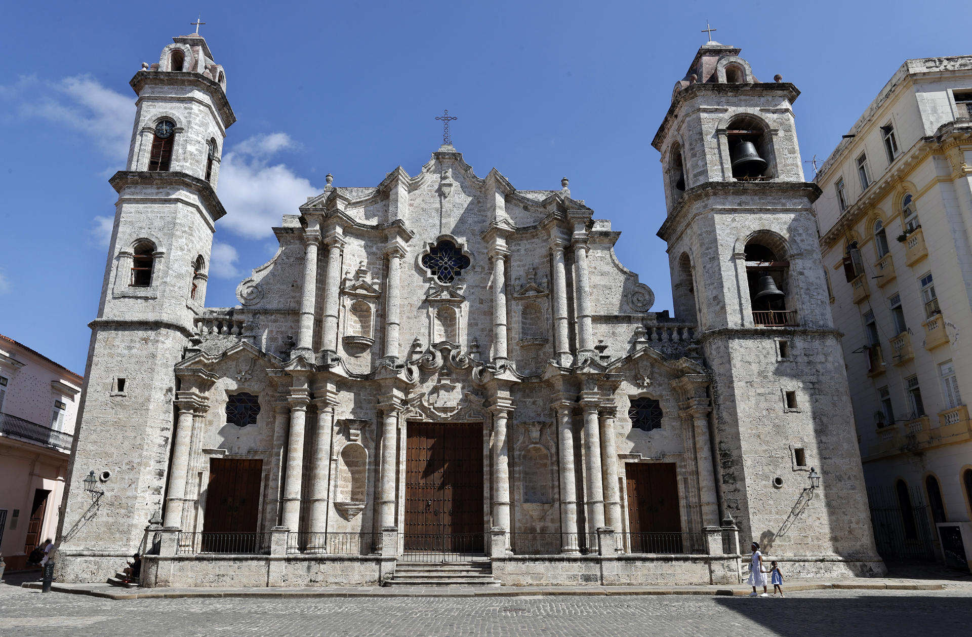 Una mujer con una niña caminan frente a la catedral de La Habana este lunes, en La Habana (Cuba). EFE/ Ernesto Mastrascusa
