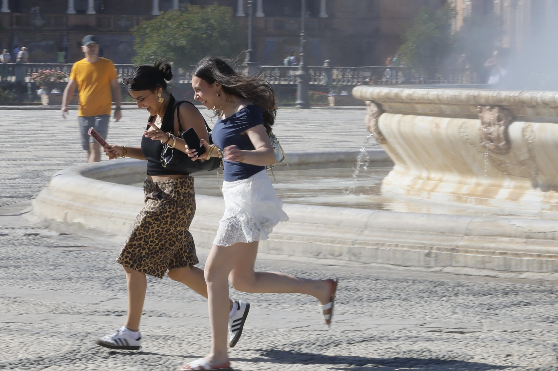 Dos mujeres caminan por la Plaza de España de Sevilla, este lunes al que acompaña el buen tiempo en Andalucía. EFE/José Manuel Vidal