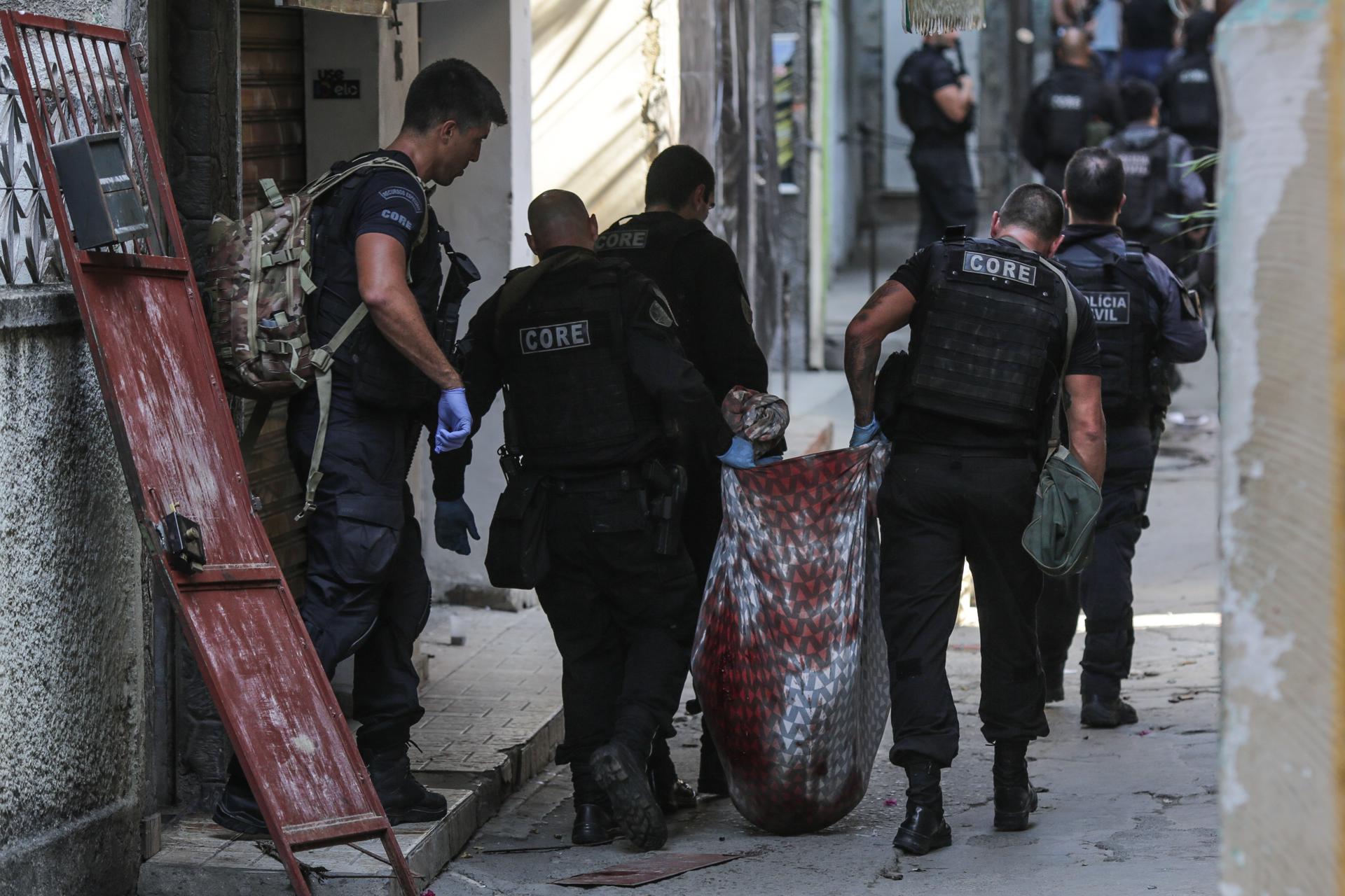 Fotografía de archivo, tomada en mayo de 2021, en la que aparece un grupo de policías al trasladar un cadáver, durante un operativo contra una banda de narcotraficantes, en un favela de Río de Janeiro (Brasil). EFE/André Coelho