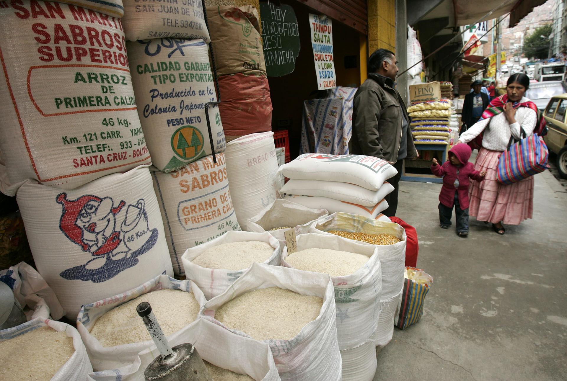 Fotografía de archivo de una mujer aimara al pasar por una venta de arroz, en La Paz (Bolivia). EFE/Martín Alipaz