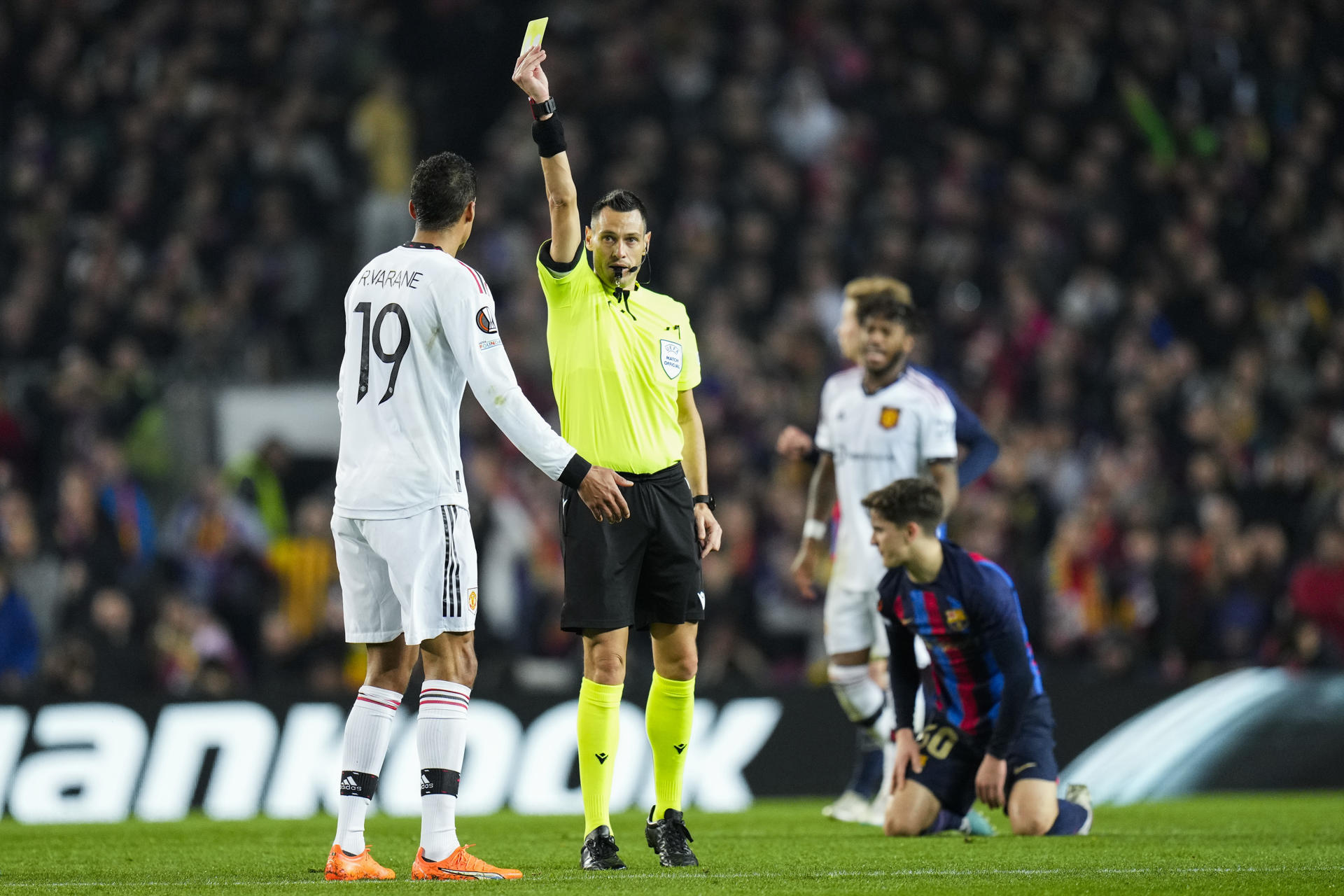 El árbitro italiano Maurizio Mariani (c) muestra la tarjeta amarilla a Raphael Varane (i), ex defensa francés del Manchester United, en una imagen de archivo. EFE/ Siu Wu