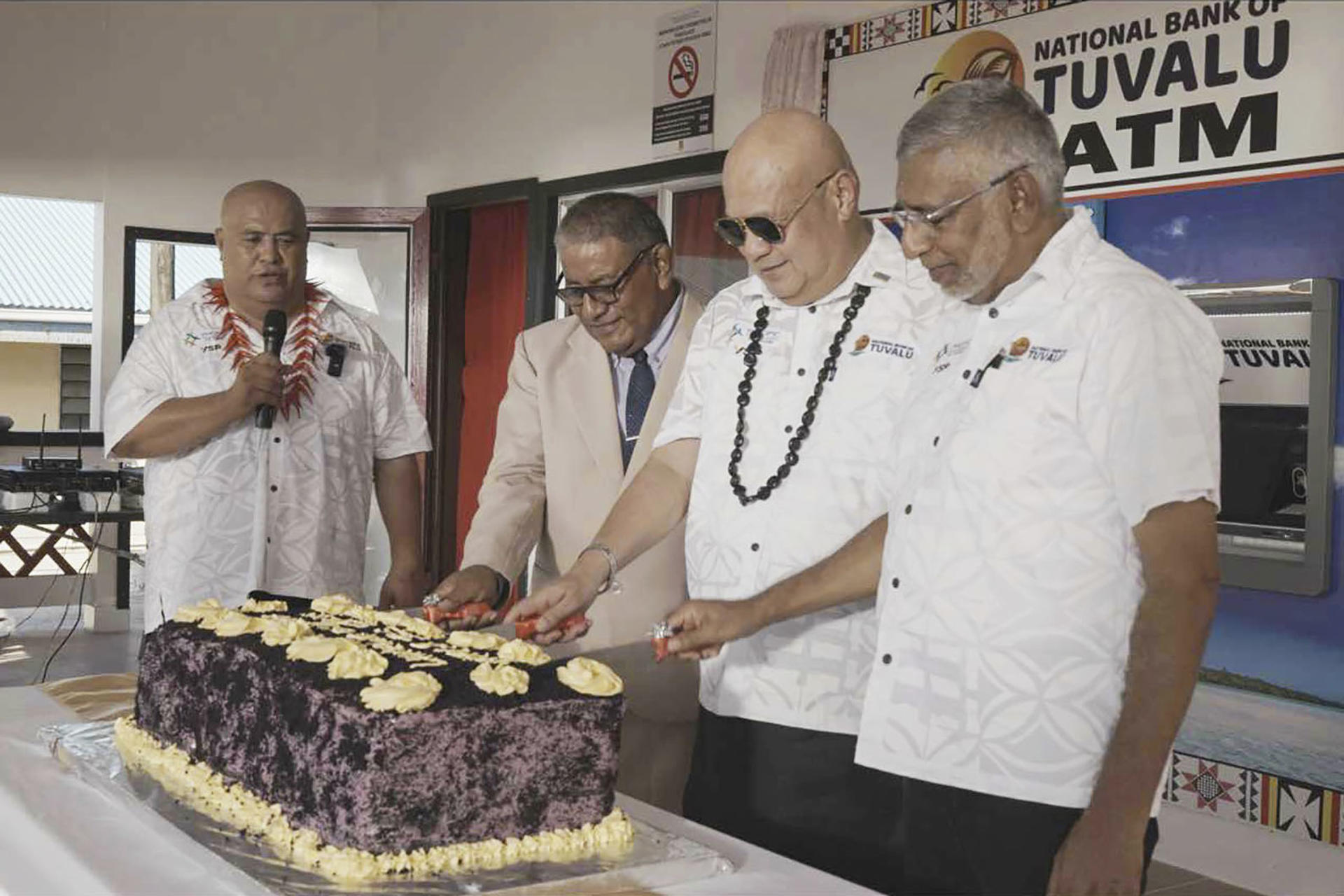 FUNAFUTI, 17/04/2025.- Tuvalu, pequeña nación insular del Pacífico con poco más de 11.000 habitantes, inauguró esta semana sus primeros cajeros automáticos, una innovación que las autoridades locales calificaron de "trascendental". El Gobierno de Tuvalu confirmó el martes la instalación en la principal isla del país, Funafuti, de cinco cajeros automáticos y 30 terminales de punto de venta que permitirán a los comercios procesar pagos electrónicos por primera vez en el país. La ceremonia de inauguración de los cajeros tuvo lugar en la sede del Banco Nacional de Tuvalu, ubicado en la aldea de Vaiaku, en Funafuti, y contó con la asistencia de figuras políticas y empresariales tuvaluanas. El primer ministro de Tuvalu, Feleti Teo (2d), junto a otros representantes políticos, cortó una tarta ante el cajero instalado en la principal entidad crediticia de la nación insular, como parte de la ceremonia de inauguración. EFE/ Tuvalu Government Media *****SOLO USO EDITORIAL/SOLO DISPONIBLE PARA ILUSTRAR LA NOTICIA QUE ACOMPAÑA (CRÉDITO OBLIGATORIO) *****