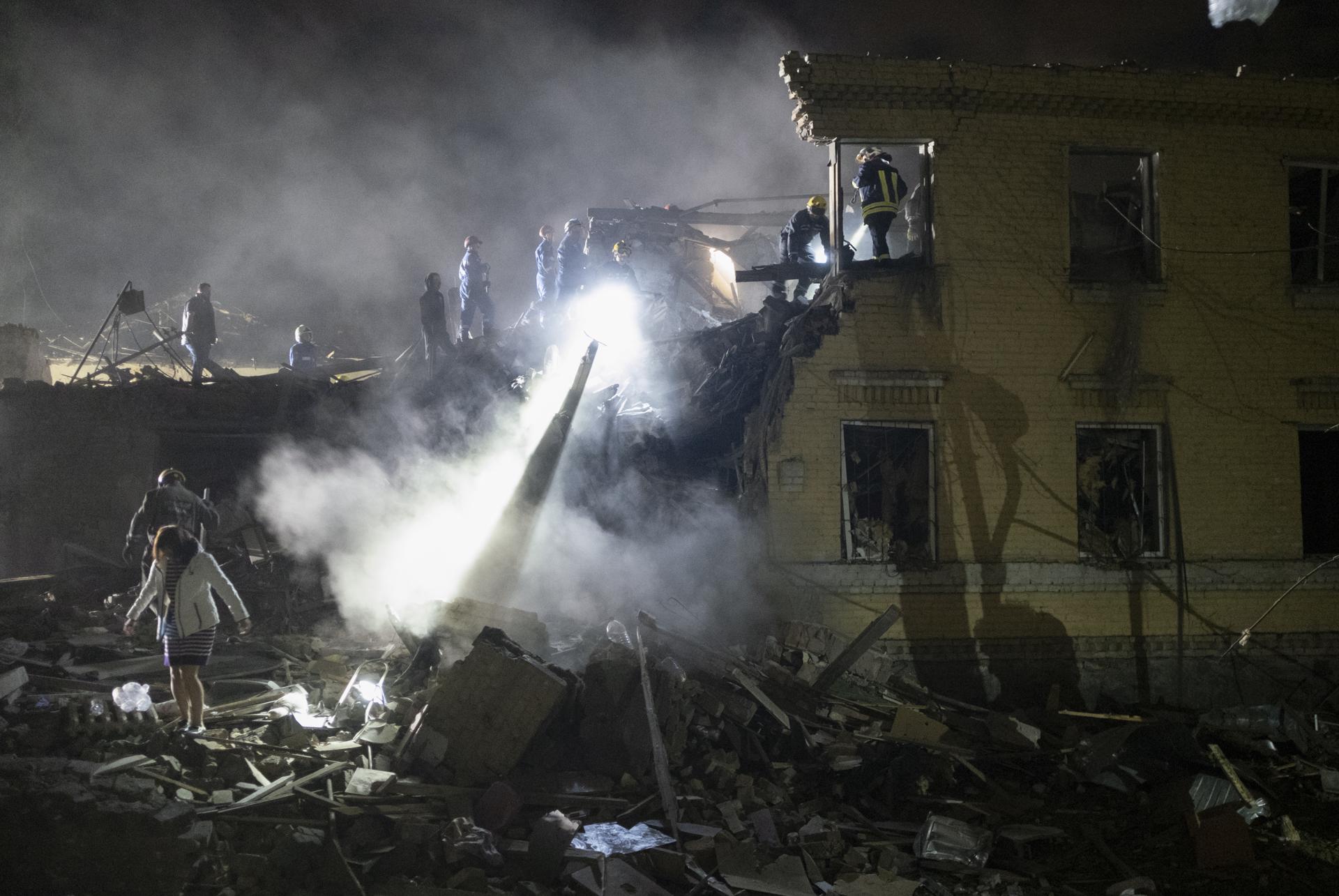 Rescatistas ucranianos trabajan en el lugar donde un cohete impactó esta noche contra un edificio residencial en Kiev. EFE/EPA/SERGEY SHESTAK