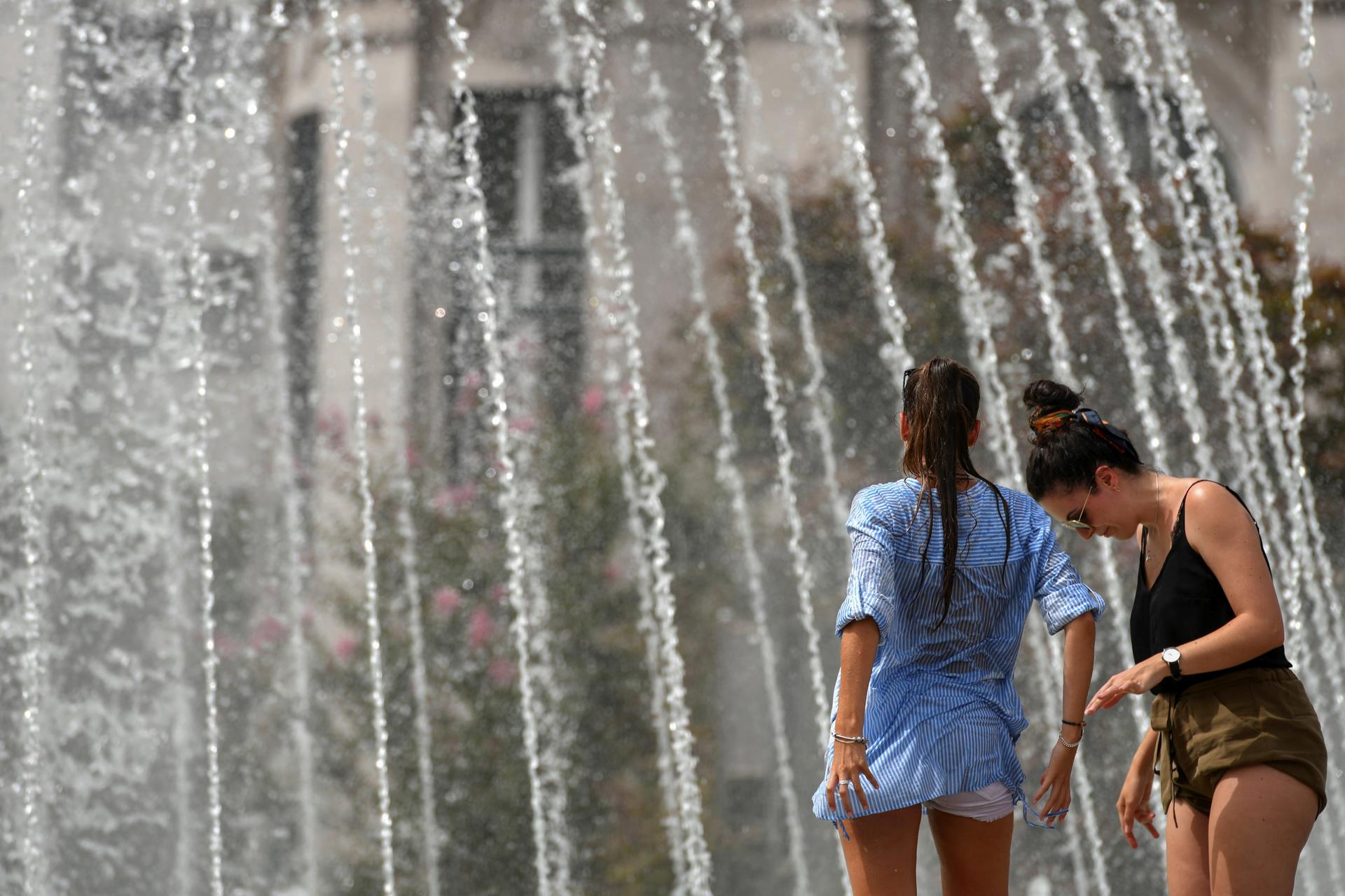 Dos jóvenes se refrescan en una fuente en Braga, Portugal, en una imagen de archivo. EFE/HUGO DELGADO