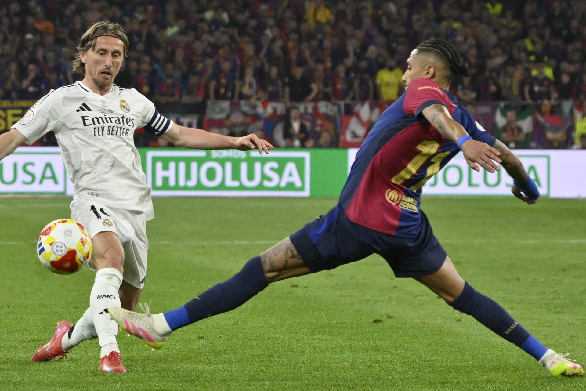 El centrocampista croata del Real Madrid Luka Modric (i) pelea un balón con el delantero brasileño del Barcelona Raphinha durante la final de la Copa del Rey que disputaron Real Madrid y FC Barcelona en el estadio de La Cartuja, en Sevilla. EFE/Raúl Caro