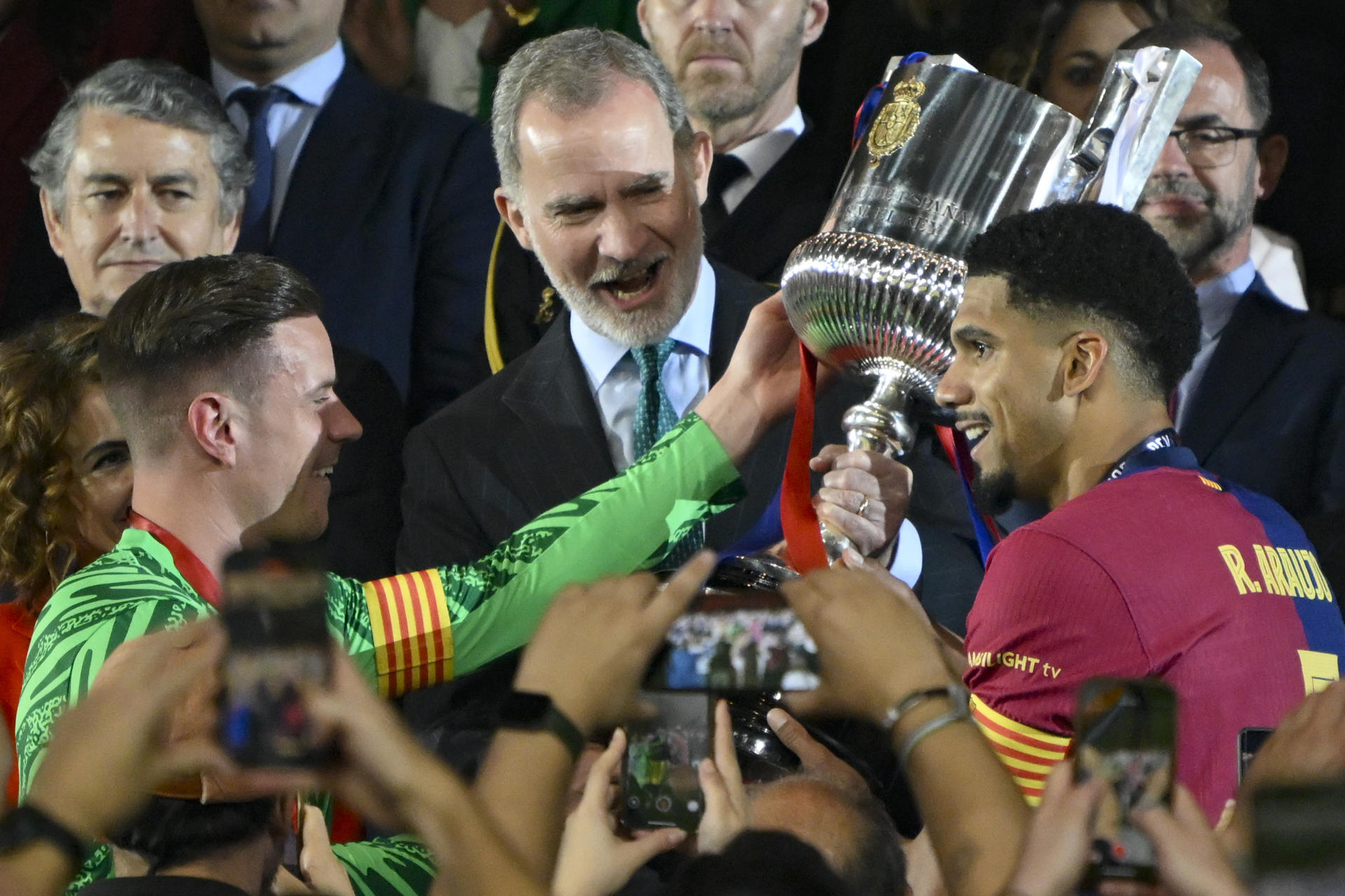 Los jugadores del FC Barcelona, el uruguayo Ronald Araujo (d) y el alemán Marc-André ter Stegen, tras recibir de manos del rey Felipe VI el trofeo de campeones de la Copa del Rey a la finalización del encuentro que han disputado Real Madrid y FC Barcelona en el estadio de La Cartuja, en Sevilla. EFE / Raul Caro.