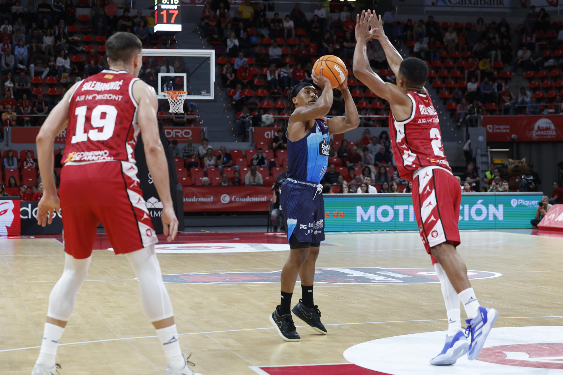 El base del Coruña Brandon Taylor (c) se dispone a lanzar ante Trae Bell-Haynes, del Casademont, durante el partido de la Liga Endesa de baloncesto que Casademont Zaragoza y Leyma Coruña disputaron en la capital aragonesa. EFE/Javier Cebollada