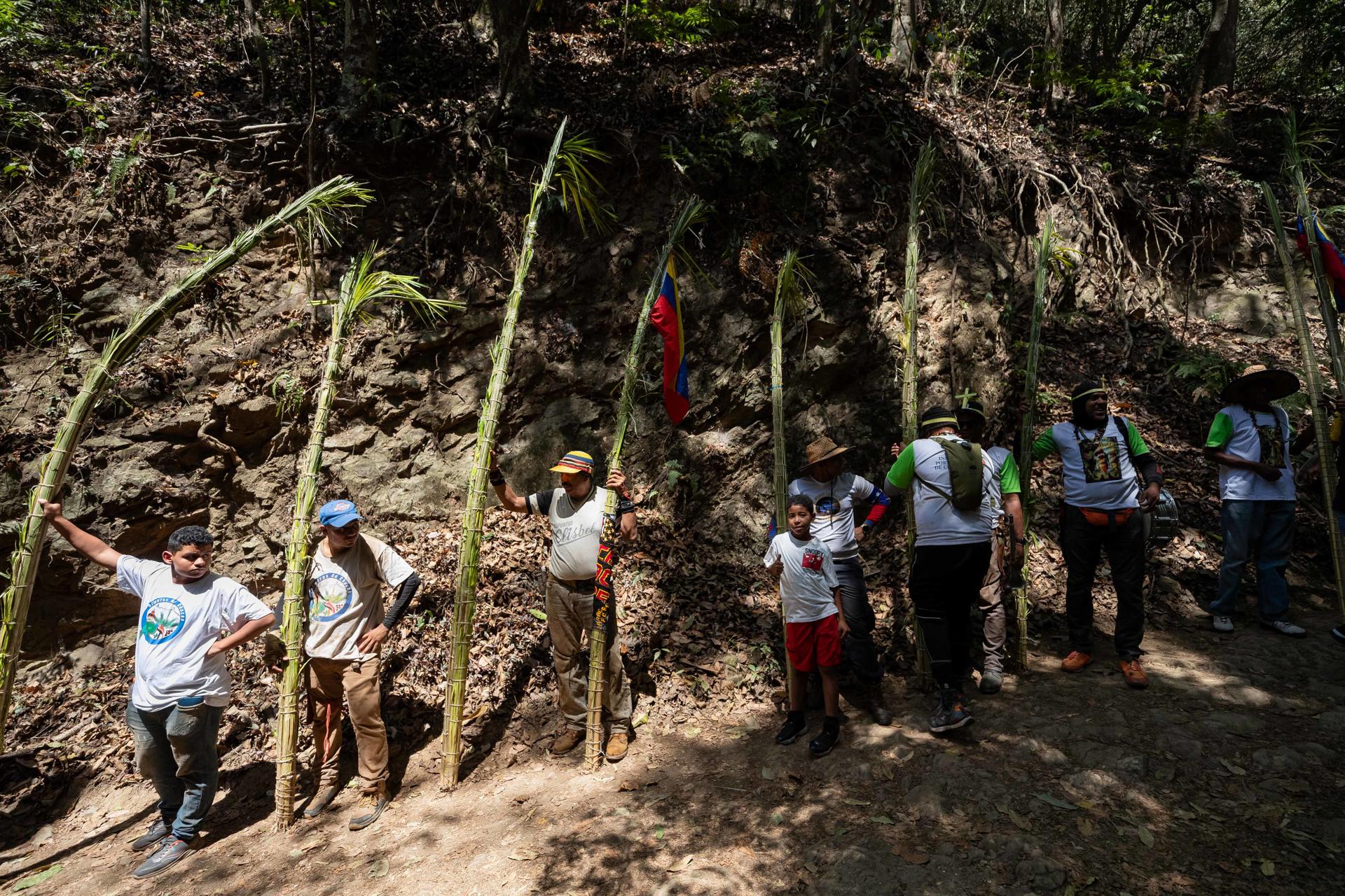 Un grupo de personas descansan junto a las hojas de palma durante la bajada de los Palmeros de Chacao este sábado, en Caracas (Venezuela). EFE/ Ronald Peña