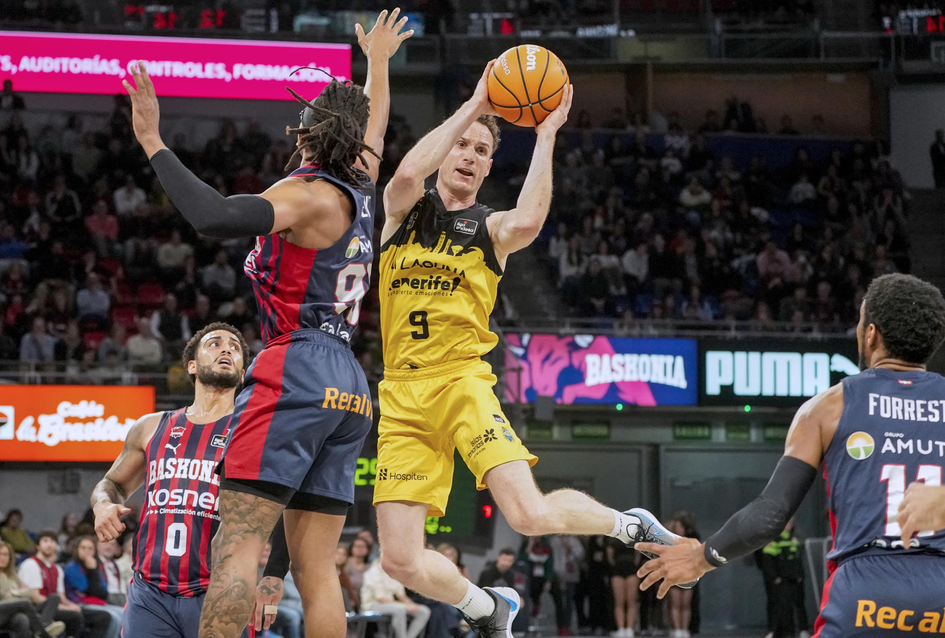 El jugador del Baskonia Chima Moneke intenta taponar a Marcelinho Huertas, del Laguna Tenerife, durante el partido de Liga Endesa que disputaron en el pabellón Santiago Martín de La Laguna. EFE/L. RICO