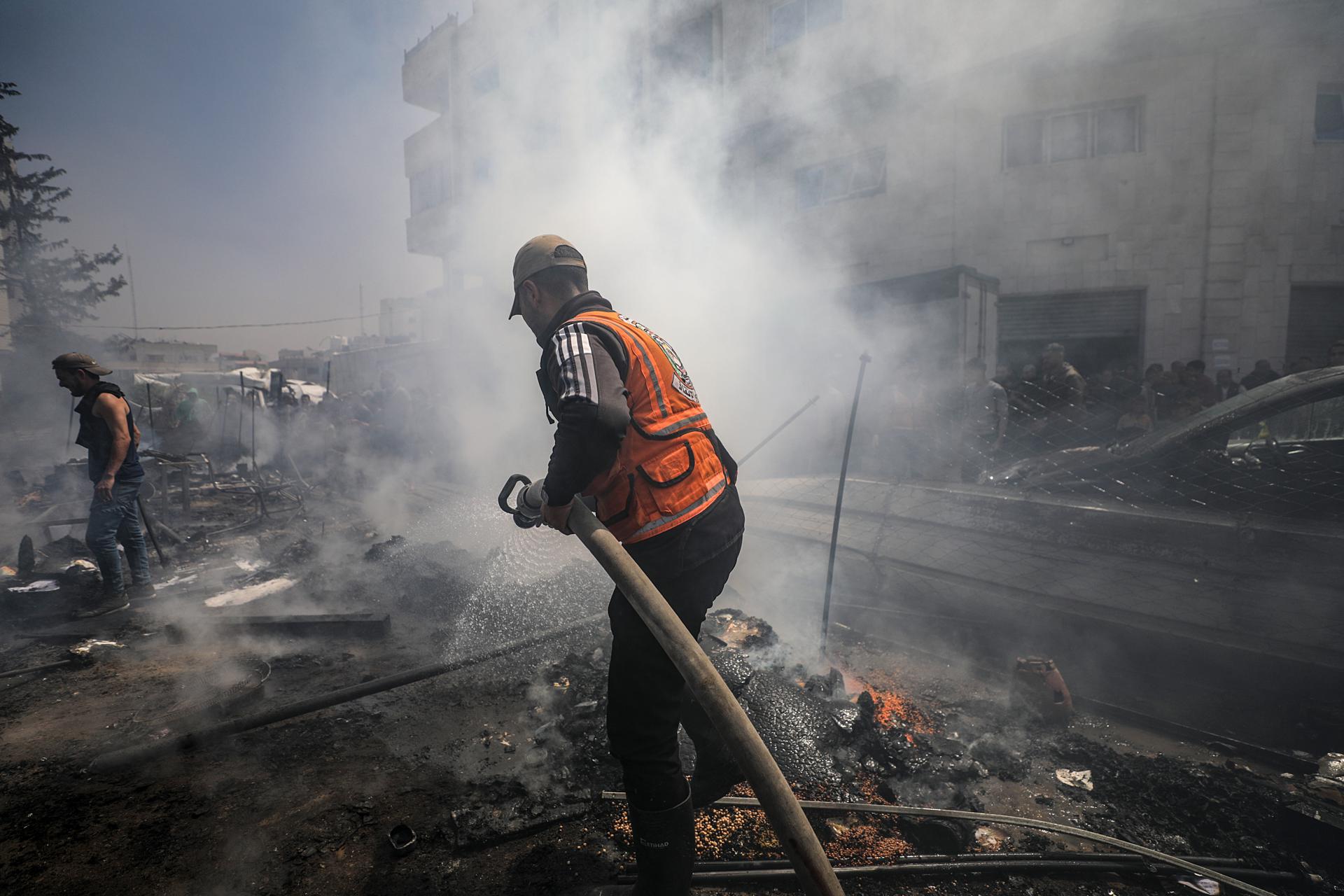 Un trabajador de la defensa civil palestina apaga el fuego de una tienda de campaña tras un ataque israelí el 21 de abril de 2025. EFE/EPA/MOHAMMED SABER