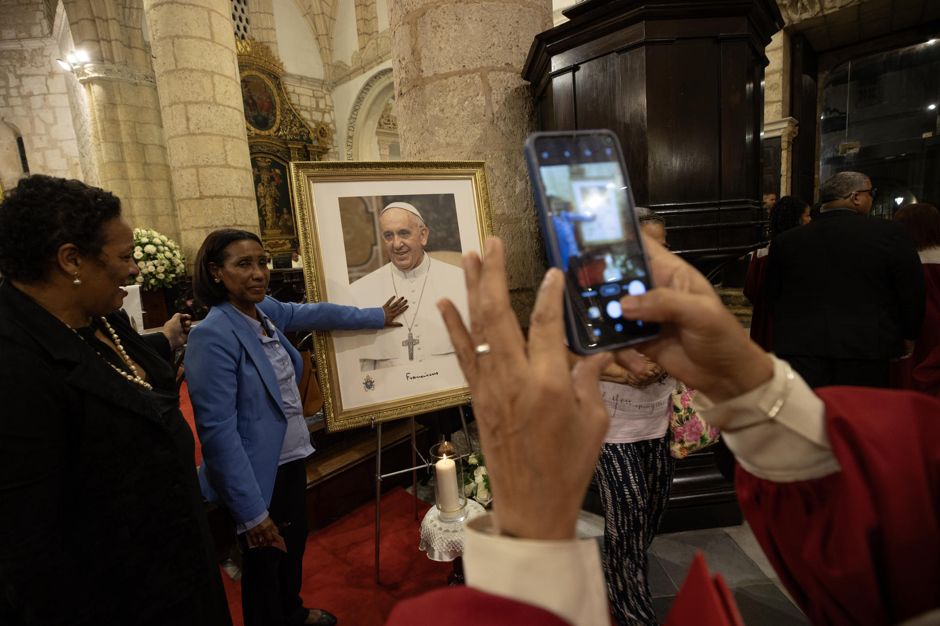Personas posan al lado de una imagen del papa Francisco durante la celebración de una misa en su memoria, este jueves en Santo Domingo (República Dominicana). EFE/Orlando Barría