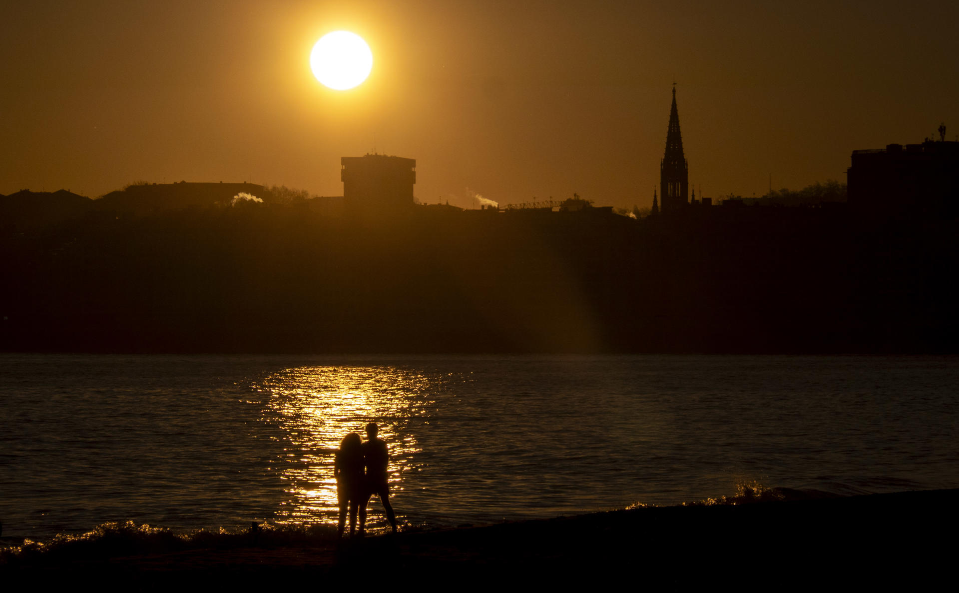 Una pareja observa el amanecer este martes en San Sebastián. EFE/Javier Etxezarreta