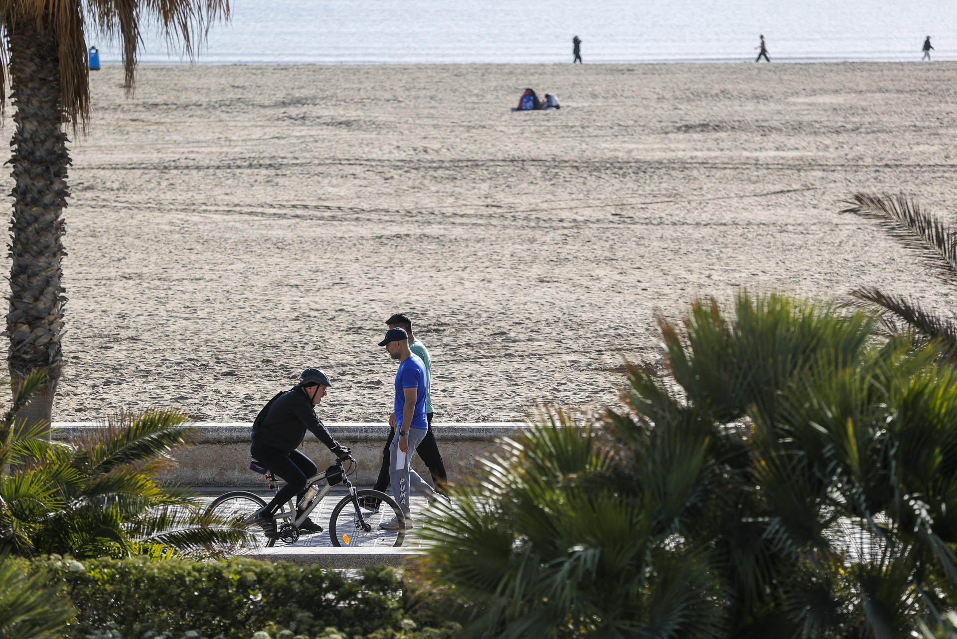 Varias personas pasean por el paseo marítimo de la playa de la Malavarrosa durante este lunes. EFE/Manuel Bruque