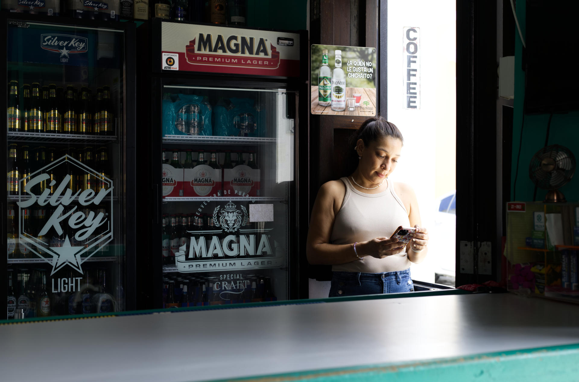 Una mujer que observa un teléfono celular fue captada este miércoles, 16 de abril, en la puerta de una tienda, durante un apagón eléctrico, en San Juan (Puerto Rico). EFE/Thais Llorca