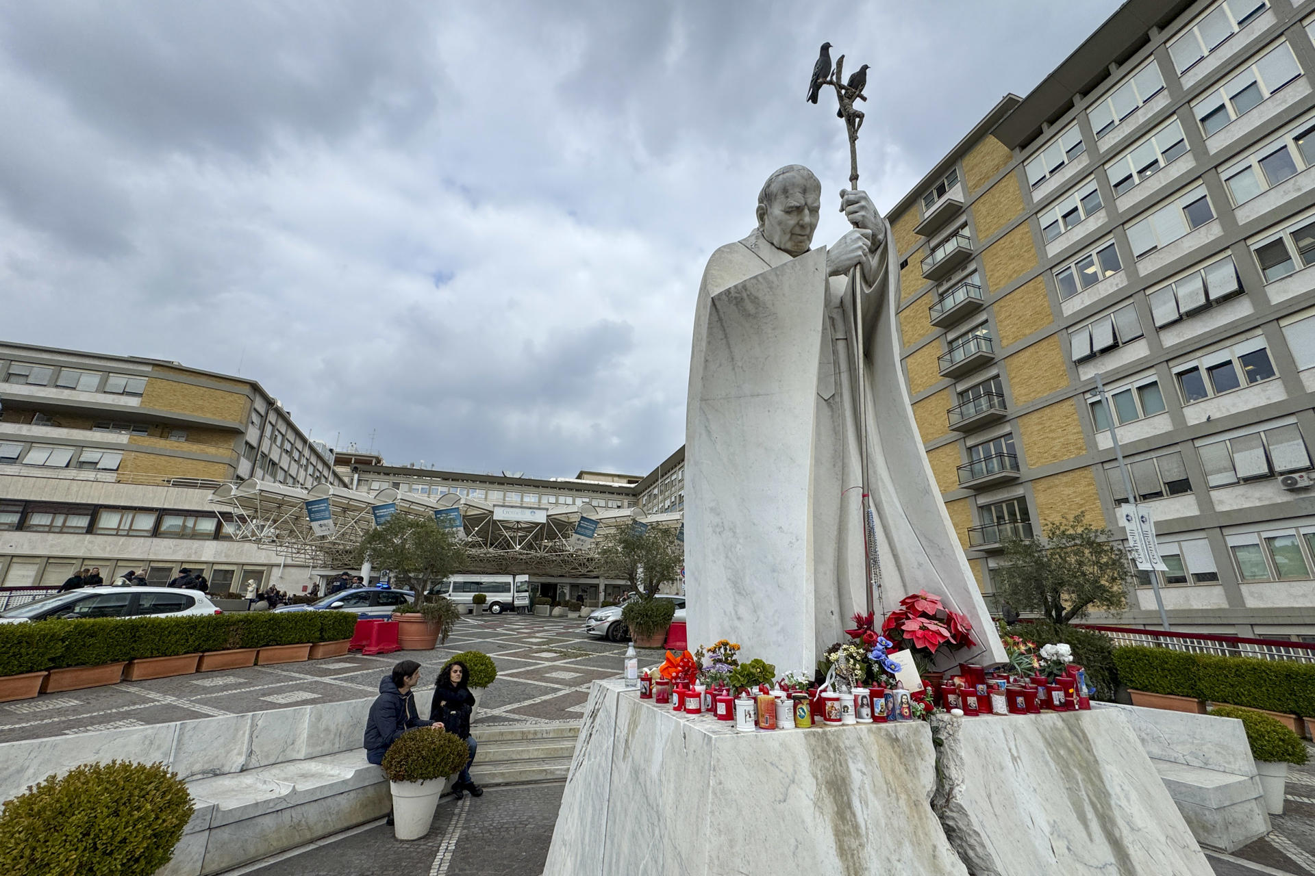 Imagen de las elas y flores a los pies de la escultura de Juan Pablo II a las puertas del Hospital Gemelli de Roma. EFE/Daniel Cáceres