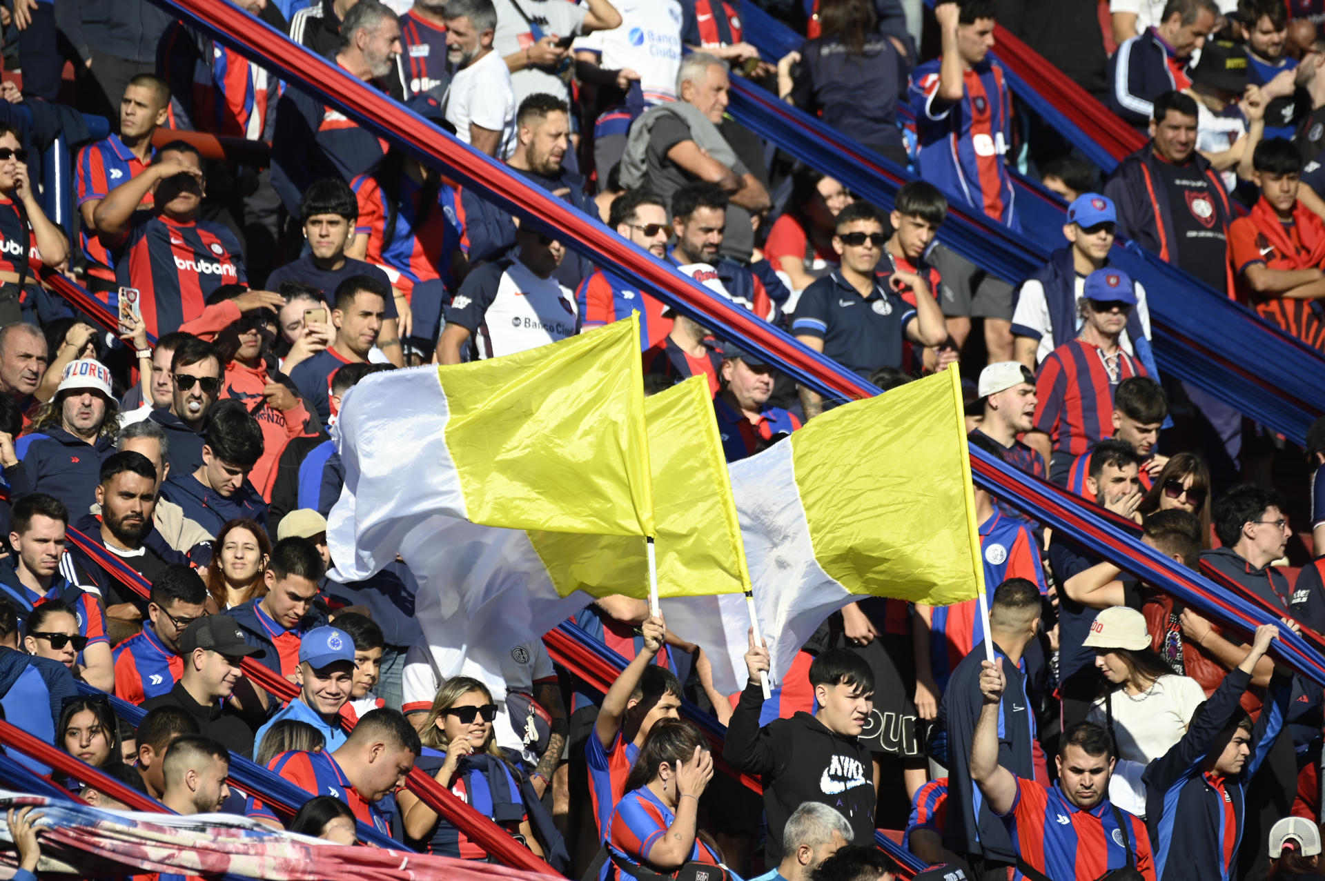 Aficionados de San Lorenzo ondean las banderas con los colores blanco y amarillo del Vaticano en el estadio Nuevo Gasómetro en Buenos Aires (Argentina). EFE/ Stringer
