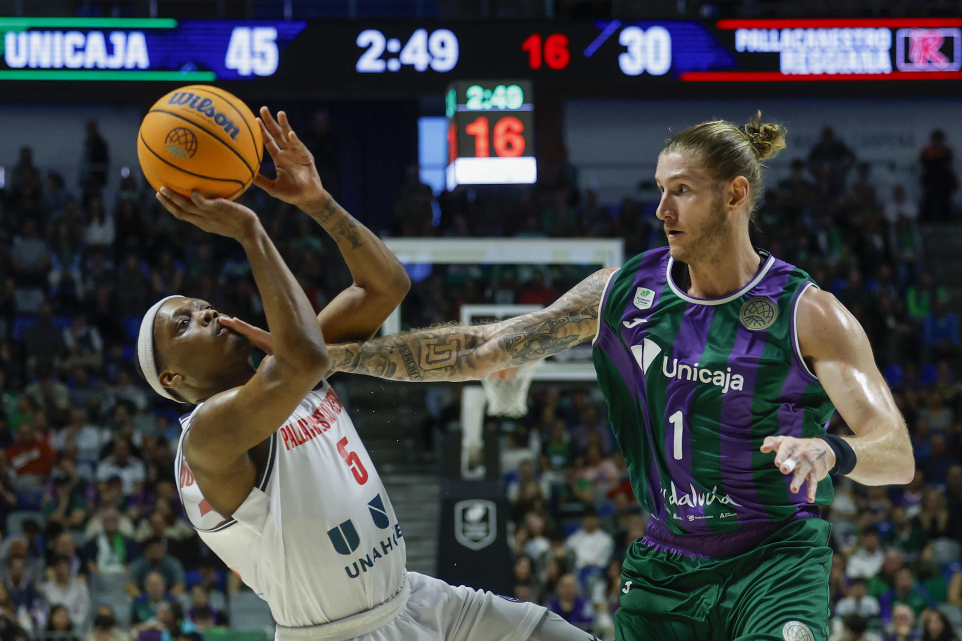 El base estadounidense de Reggiana, Cassius Winston (i), intenta lanzar ante el pivot estadounidense de Unicaja, Dylan Osetkowski, en foto del partido de ida en Málaga de Jorge Zapata. EFE