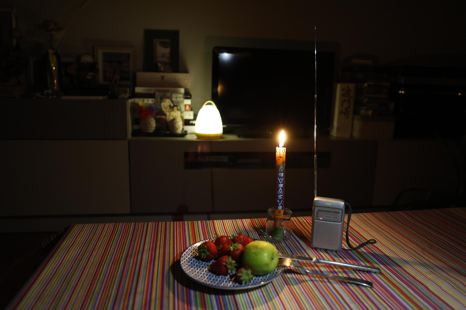Imagen de una mesa con fruta para la cena, una radio y una vela durante el apagón de este lunes. EFE/Toni Albir
